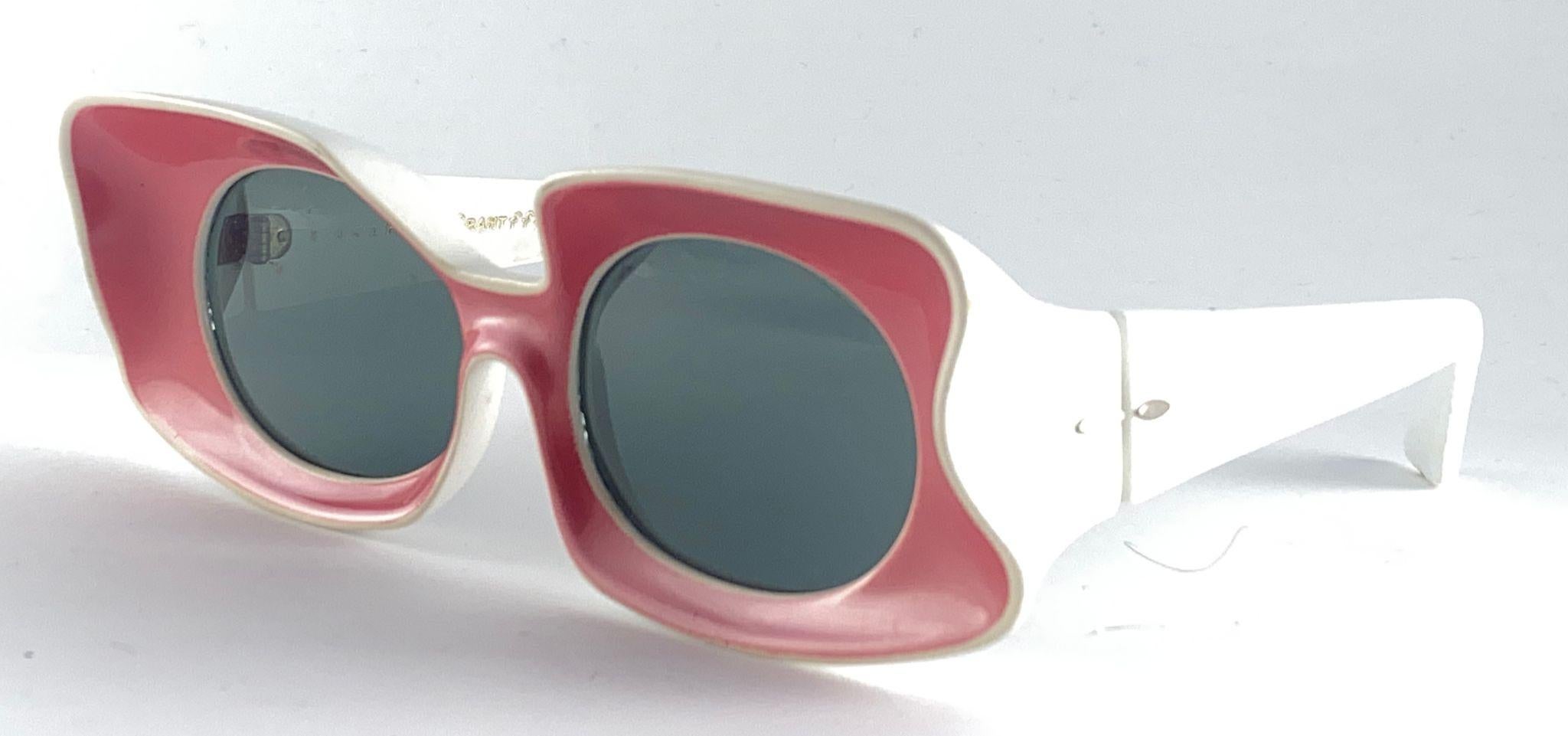 Montatura vintage di Grant Foster Grant Sculptured Cream and Pink, lenti medie grigie.

Si prega di notare che questo articolo presenta segni di usura sulla montatura e lievi graffi sulle lenti.

Made In Usa.

Anteriore : 15 cm 
Altezza della lente: