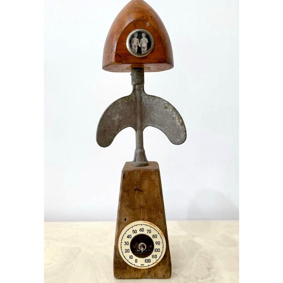 Una scultura vintage di assemblaggio unica nel suo genere che mescola cimeli industriali e figurazioni surreali. Realizzato con legno invecchiato, metallo fuso e un quadrante di tachimetro riutilizzato, questo pezzo presenta una forma scultorea che