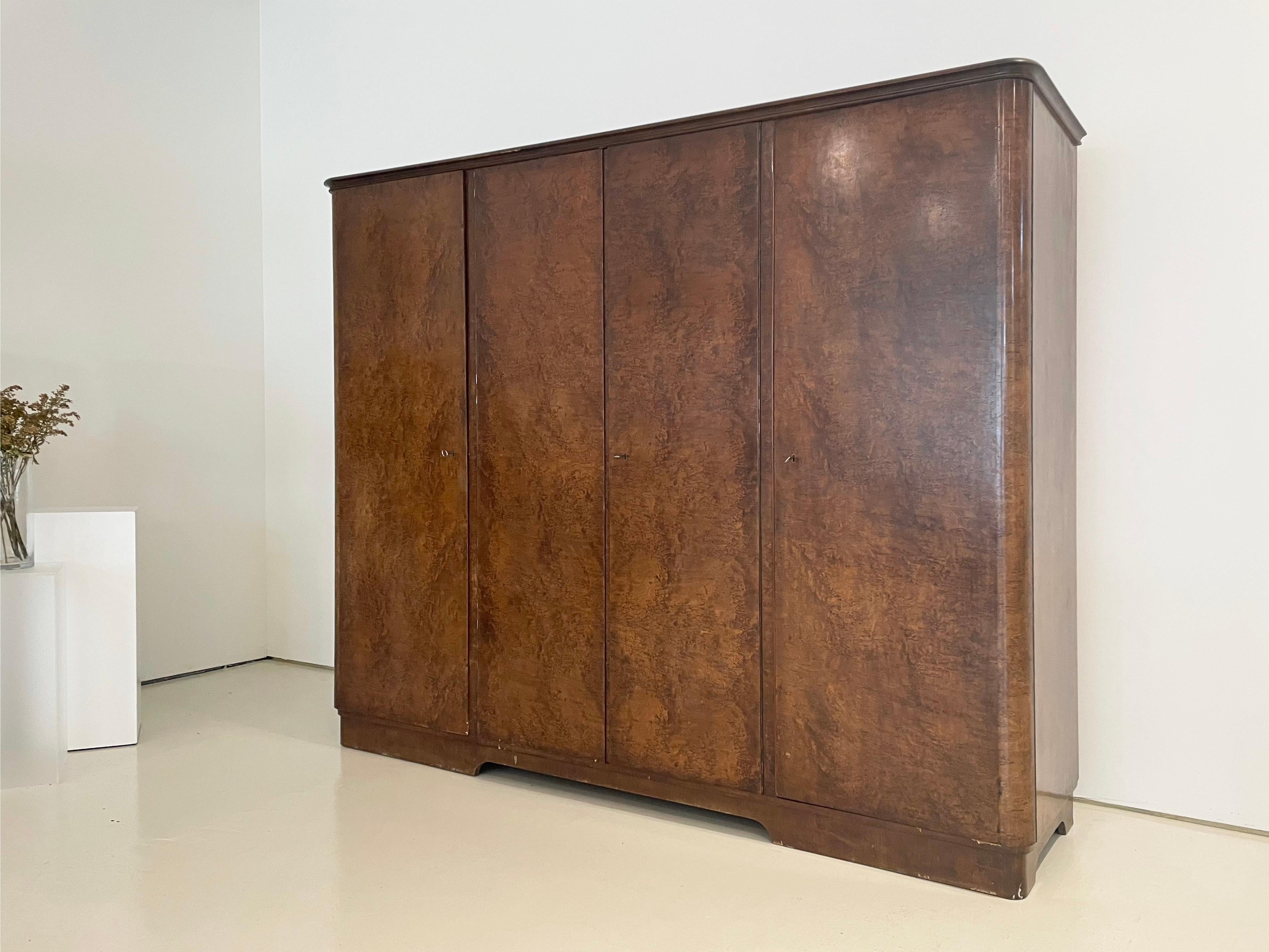 Armario vintage único, hecho a medida en estilo Art Déco

Puertas y laterales chapados en arce teñido en un rico tono nogal. 

Bonitos laterales curvados y molduras 

Cajones y estantes interiores tipo bandeja. Varias de las baldas son