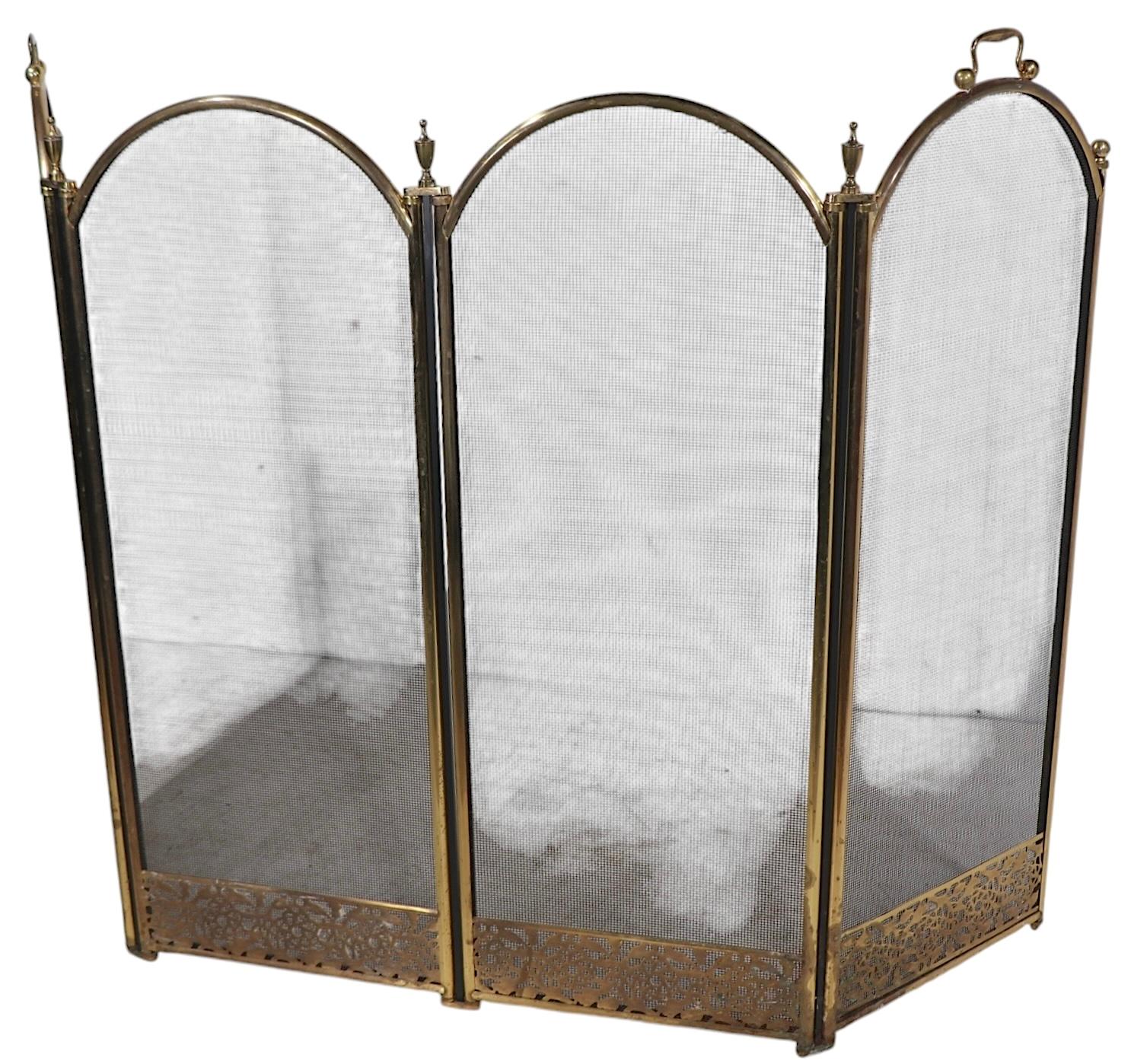Nice vintage four fold fireplace screen, spark guard, having arched panels, with a tubular brass frame, and black metal mesh screening. The two outer  panels have  bale form swing handles.
 This example is in good, original, ready to use condition,