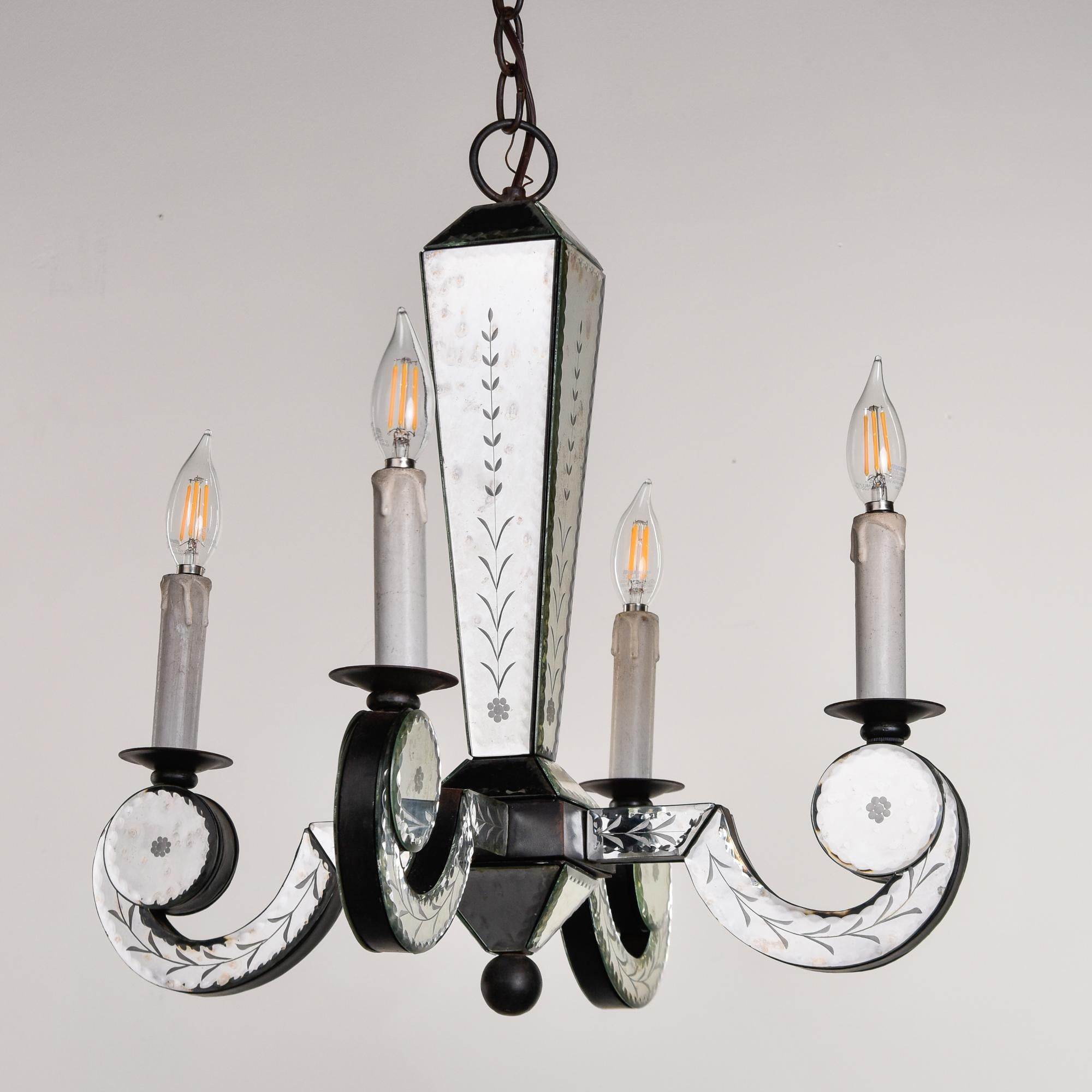 Trovato negli Stati Uniti, questo lampadario a quattro luci risale agli anni Sessanta. L'apparecchio ha una base in legno rivestita da pannelli a specchio acidati. Non sono stati riscontrati difetti. Quattro prese a candelabro. Il cablaggio è stato