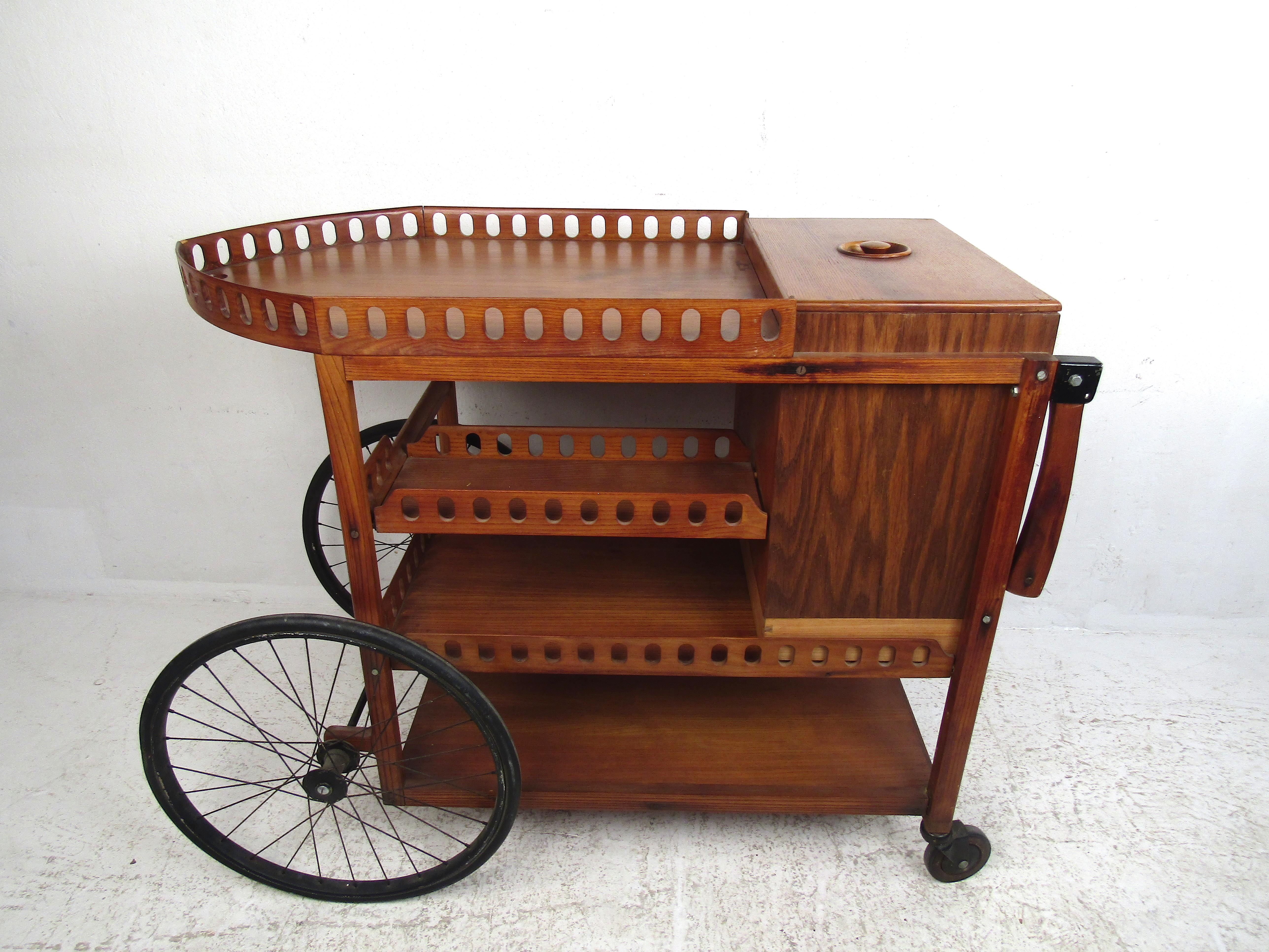 Very unusual serving cart with four tiers of storage space. Nice accents along the sides of each tier. A concealed drawer extends from the back of the piece. Easily maneuverable. Serve your guests in style with this interesting bar-cart. Please