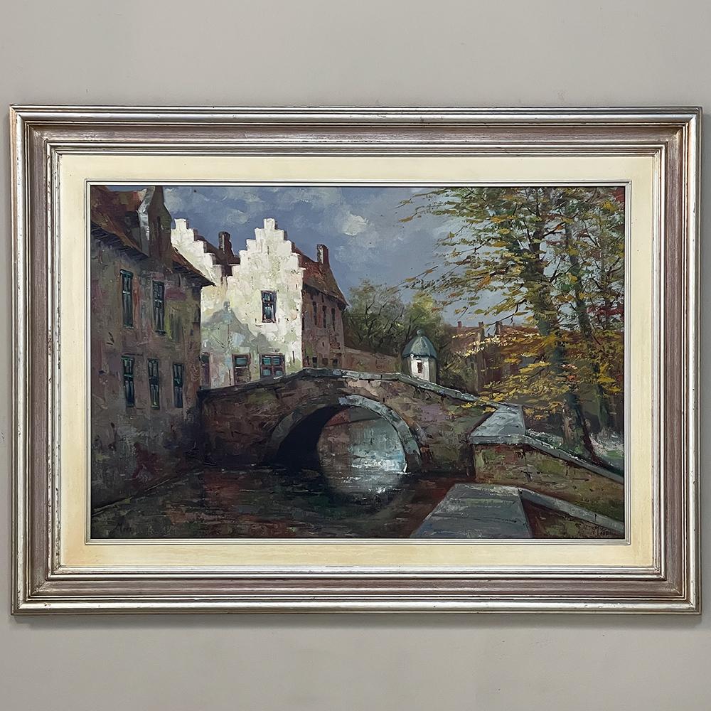 Vintage Framed Oil Painting on Canvas by Mees is a charming post-impressionistic rendering of a quaint Belgian town along the canal. Such canals were integral to most villages, providing a means to transport goods from town to town, as well as