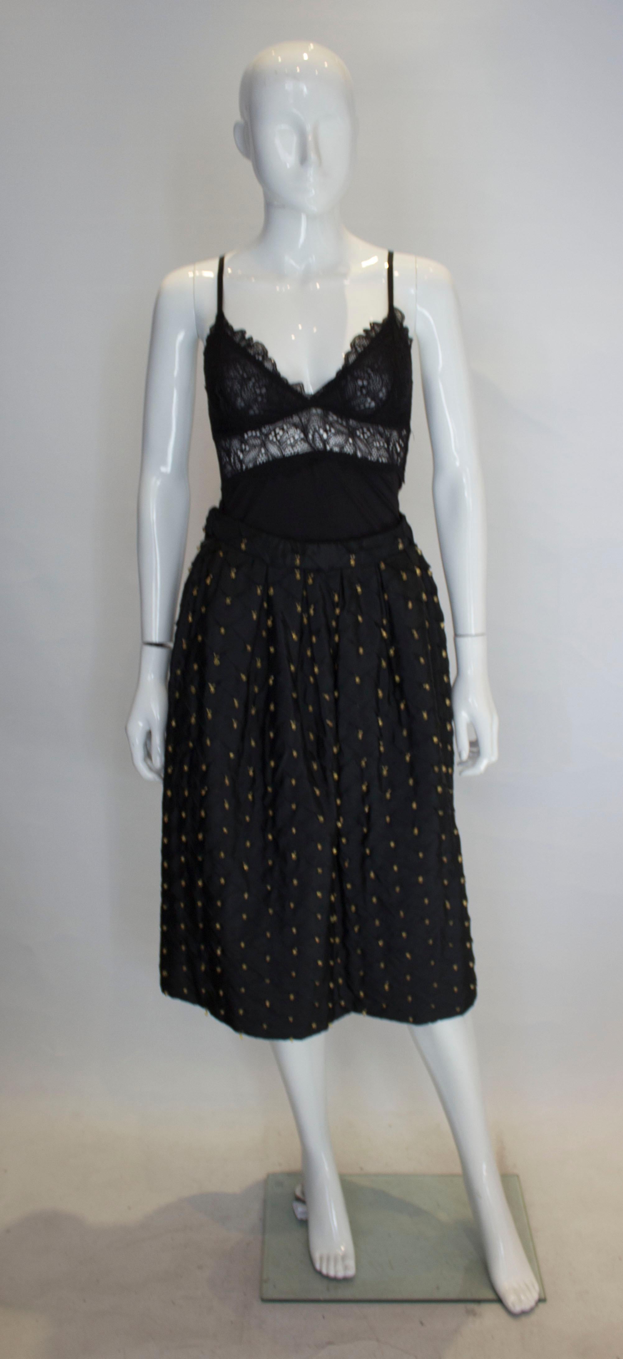 Una maravillosa falda vintage del diseñador italiano Franco Bertoli. La falda es de seda y está totalmente forrada con una cremallera lateral. Hay un detalle de pliegues por toda la falda con detalle de abalorios en forma de bulbo.