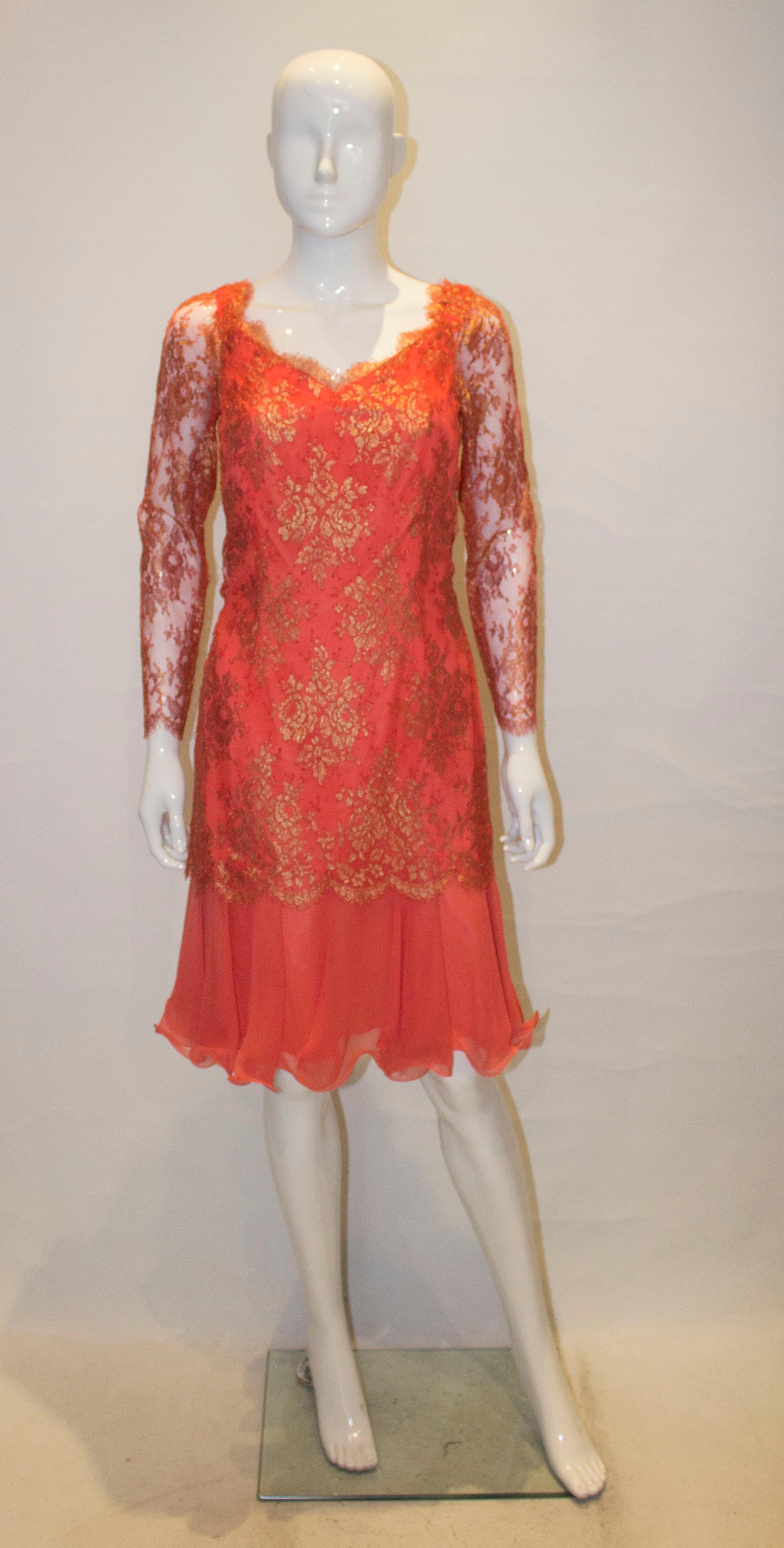 A headturning cocktail dress by Frank Usher. The dress is covered in orange and gold lace, with a wide frill at the hem.It has a v neckline and backline and central back zip.