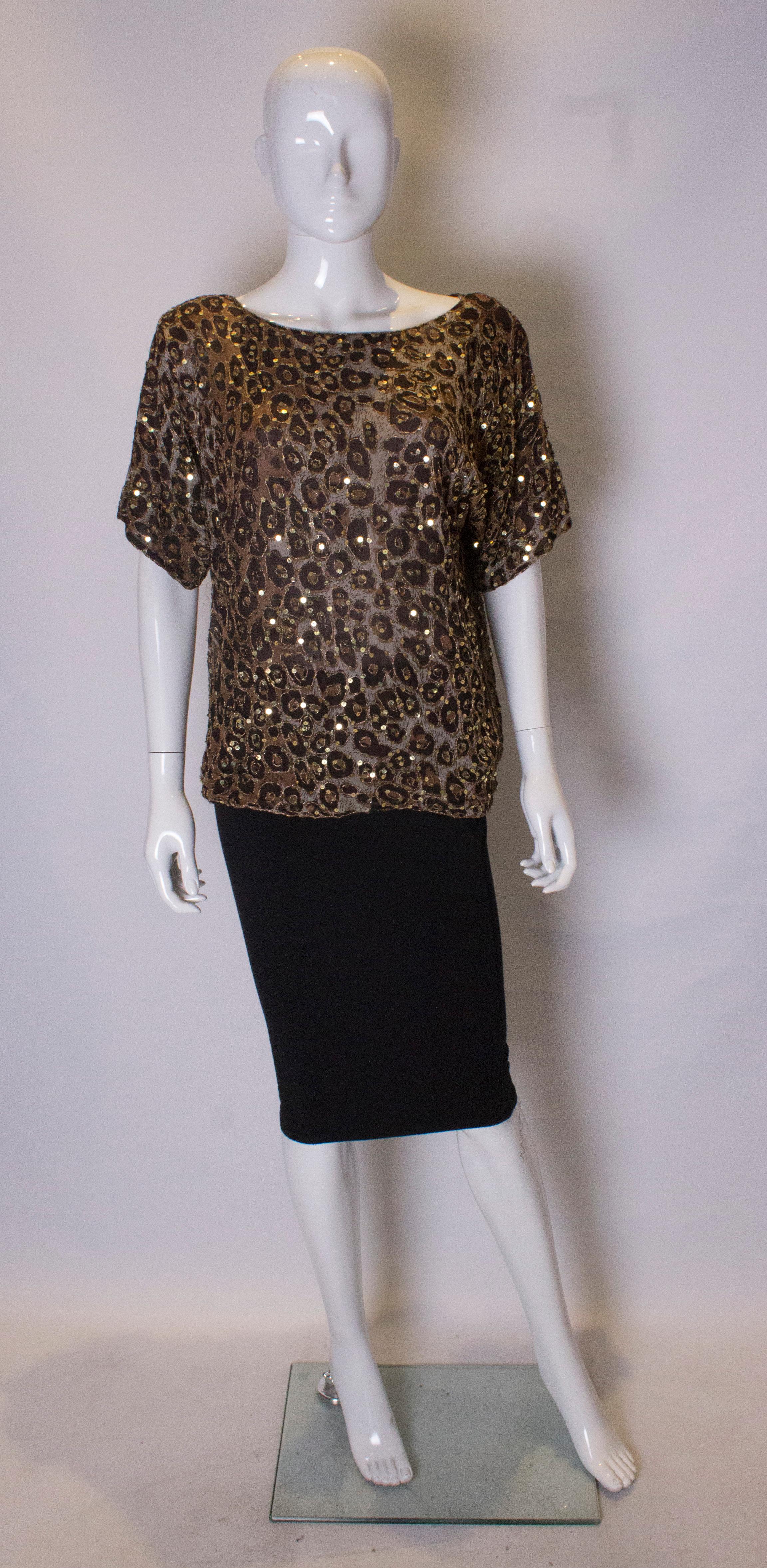 A chic and easy to wear sequin top by Frank Usher. In an attractive print in gold and brown with sequin detail. The outer fabric is silk, and it is fully lined.
