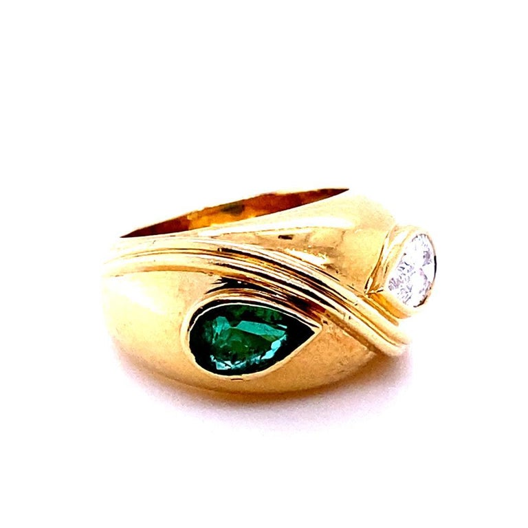 A vintage Fred Paris diamond and emerald 18 karat yellow gold bypass engagement ring.

Inspired by the Toi et Moi style this gently curving solid bombé style ring is bezel set in 18 karat yellow gold with a pear brilliant cut diamond opposite a