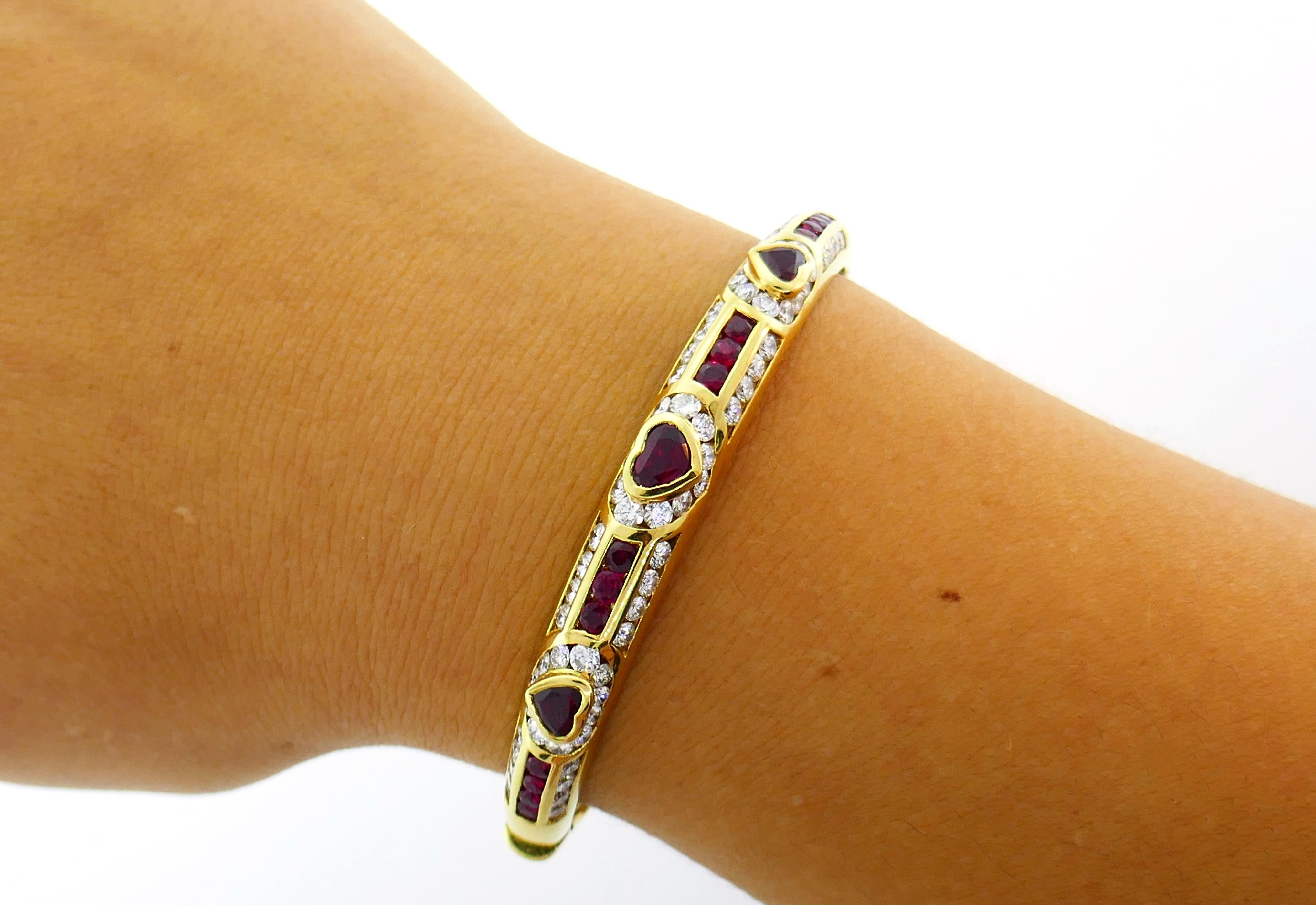 Elegant feminine bangle created by Fred Paris in the 1970s.  Made of 18 karat yellow gold, the bangle features three heart cut rubies accented with  3.35 carats round brilliant cut diamonds (F-G/VS1) and 2.50 carats round faceted rubies.