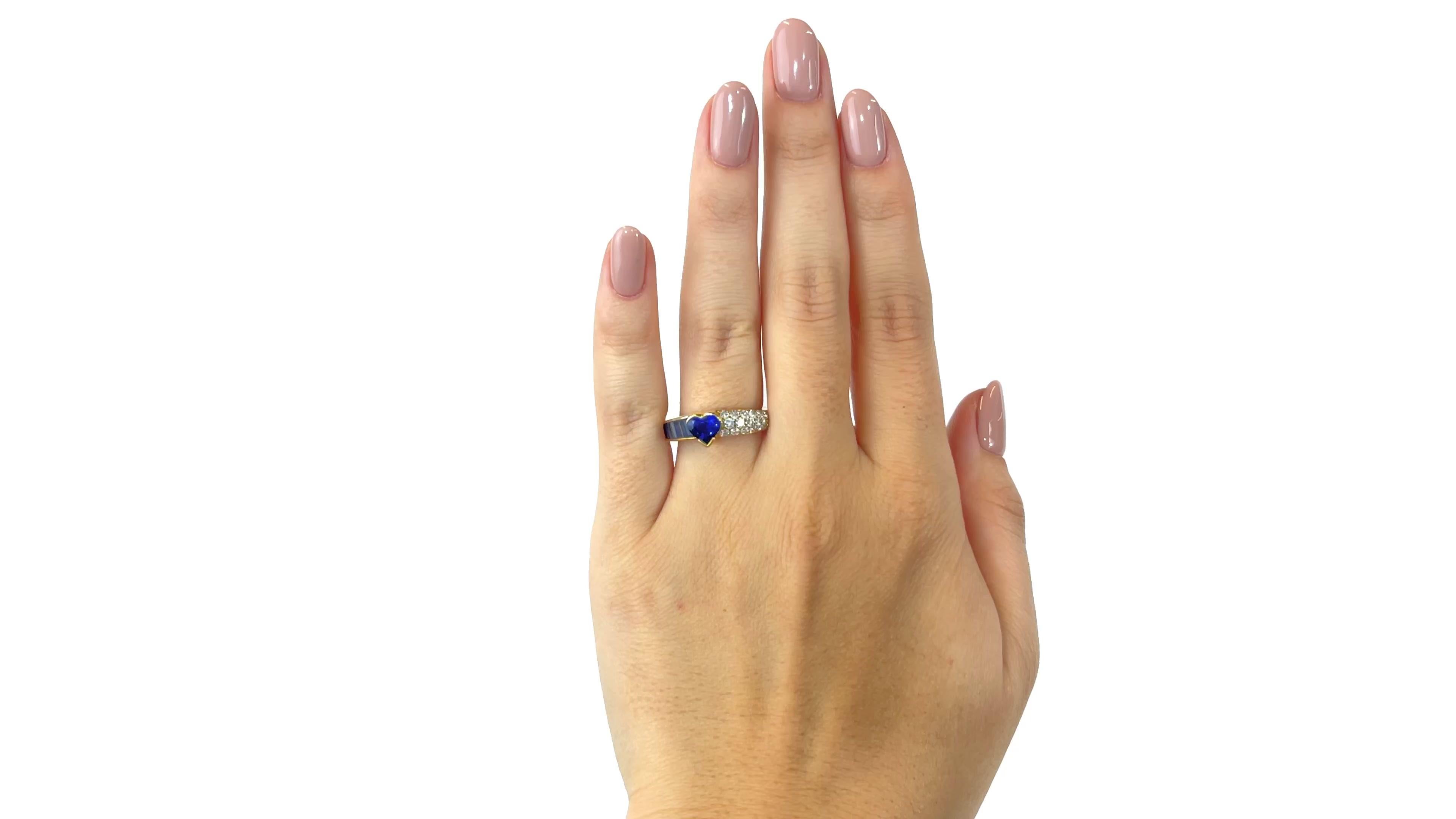 One Vintage Fred Paris Sapphire Diamond 18 Karat Gold Ring. Featuring one heart shaped sapphire weighing approximately 1.00 carat. Accented by six rectangular sapphires with a total weight of approximately 0.65 carats. Accented by 18 round brilliant