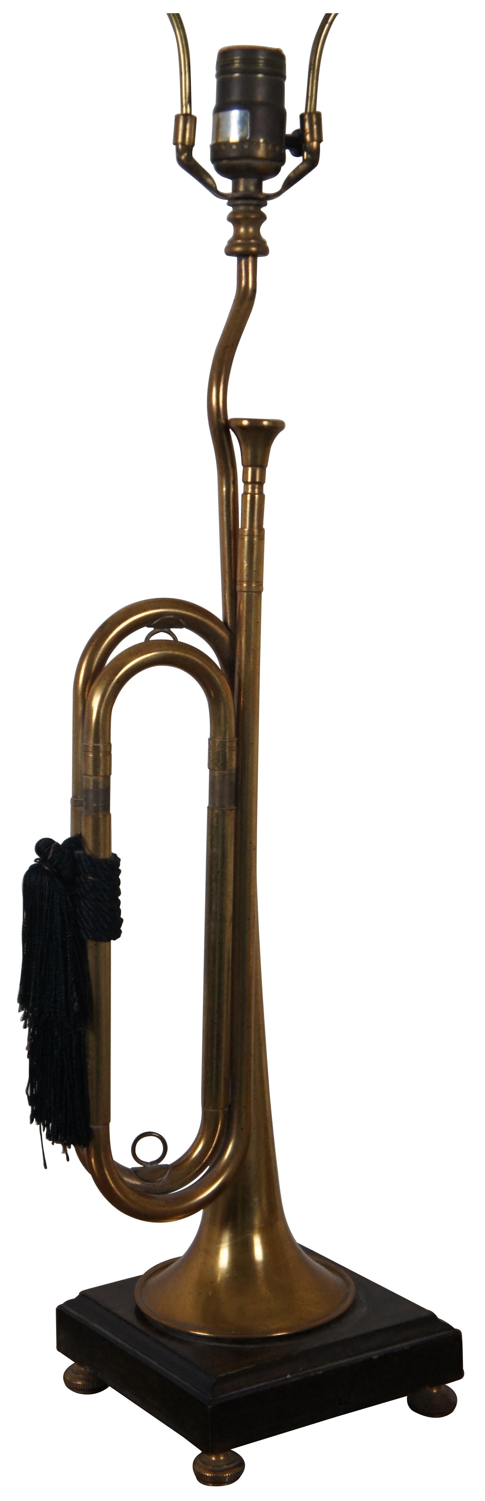 Vintage Frederick Cooper brass instrument table lamp in the shape of a bugle decorated with black tassels, standing on a dark wood base, with a ring shaped finial.

6.5” x 6” x 25.5” / Total Height – 37.5” (Width x Depth x Height)