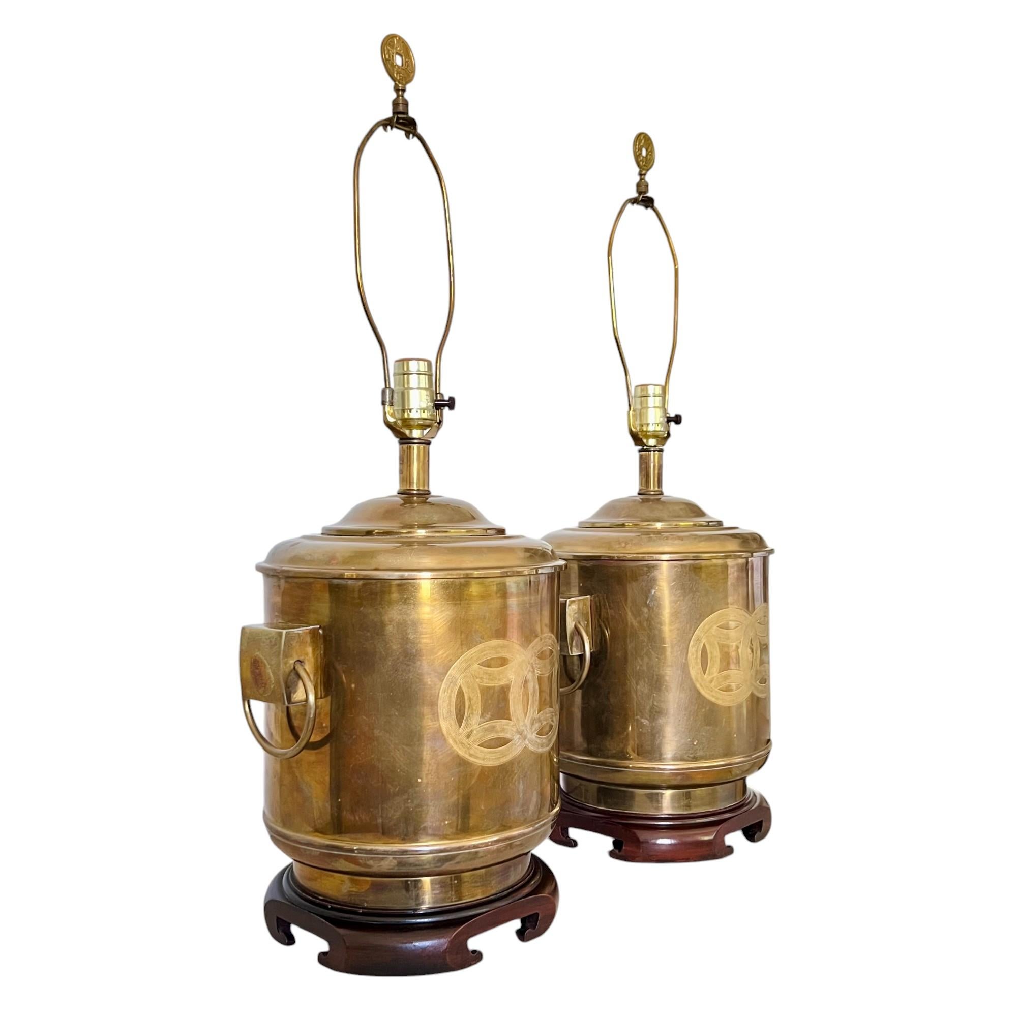 A vintage pair of chinoiserie brass drum style table lamps attributed to Frederick Cooper. Featuring Asian tea canister form bodies with etched Chinese double happiness symbols on front and back, mounted ring handles at sides and coin finials.