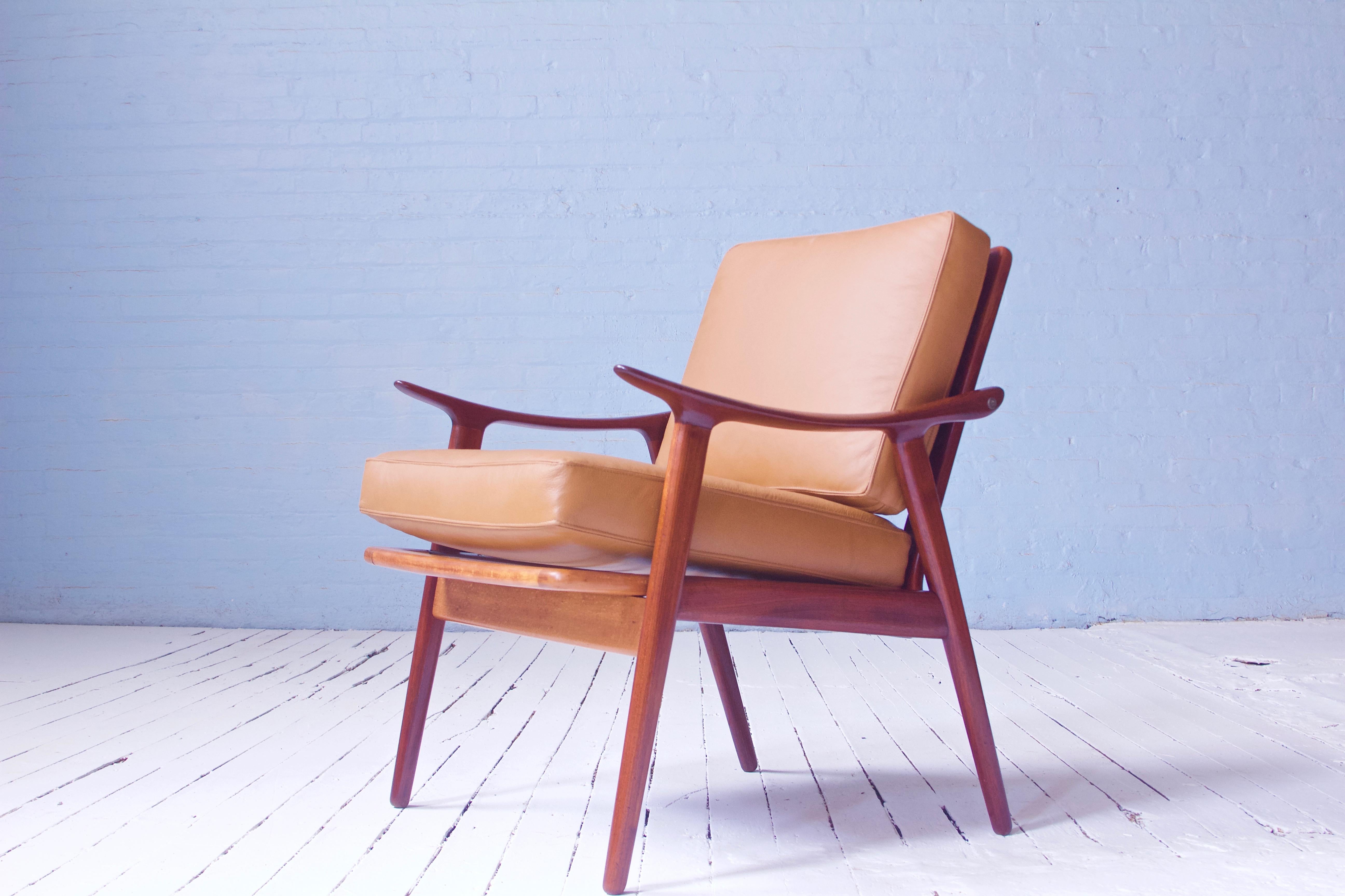 A brilliantly-conceived compact lounge chair in patinated hand-sculpted teak and cognac leather upholstery with baseball stitching designed by Norwegian industrial designer Fredrik A. Kayser, 1950s. This frame features a completely demountable