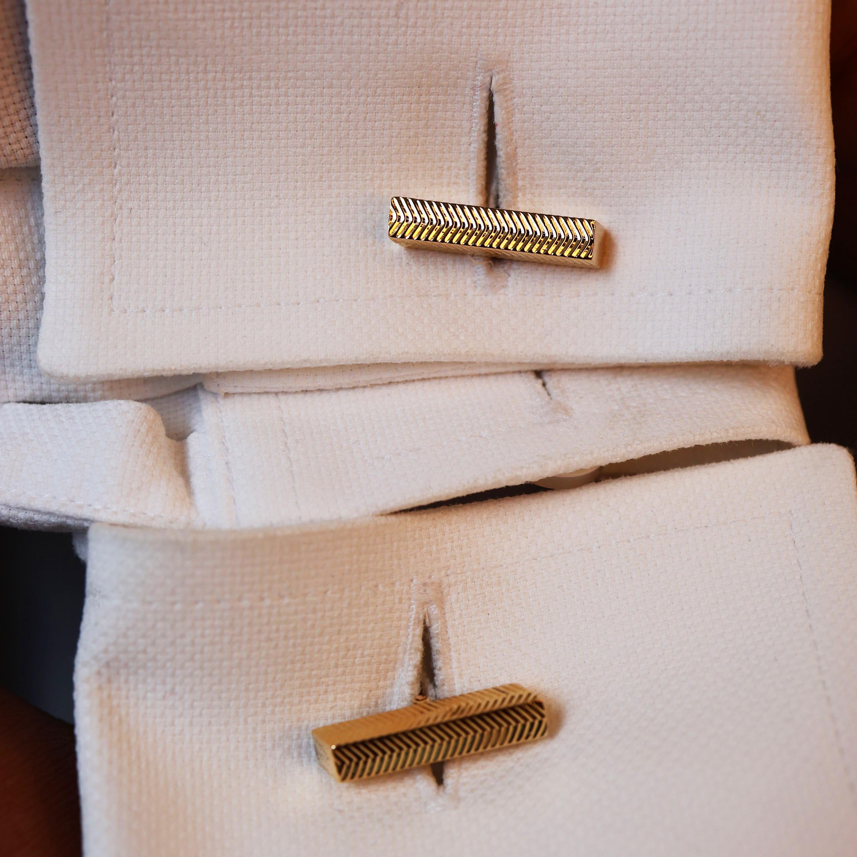 A pair of vintage, French, 18ct gold bar cufflinks, with a herringbone engraved pattern, on rectangular cross-section bars, with flat curved fixed bar links, hinged at one end, with French eagle marks and maker's mark with R bird C, circa 1960.