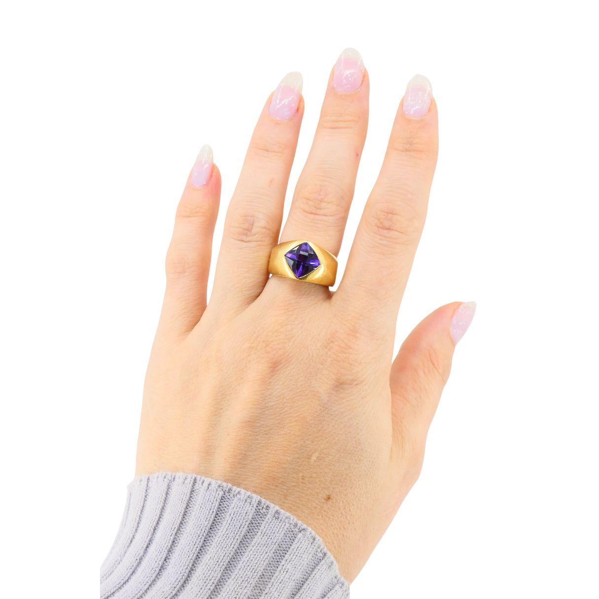 Questo elegante anello vintage francese incarna l'audace minimalismo e la precisione scultorea che hanno definito il design europeo della fine del XX secolo. Realizzato in oro giallo 18 carati, presenta una vivida ametista crisscut (tagliata a