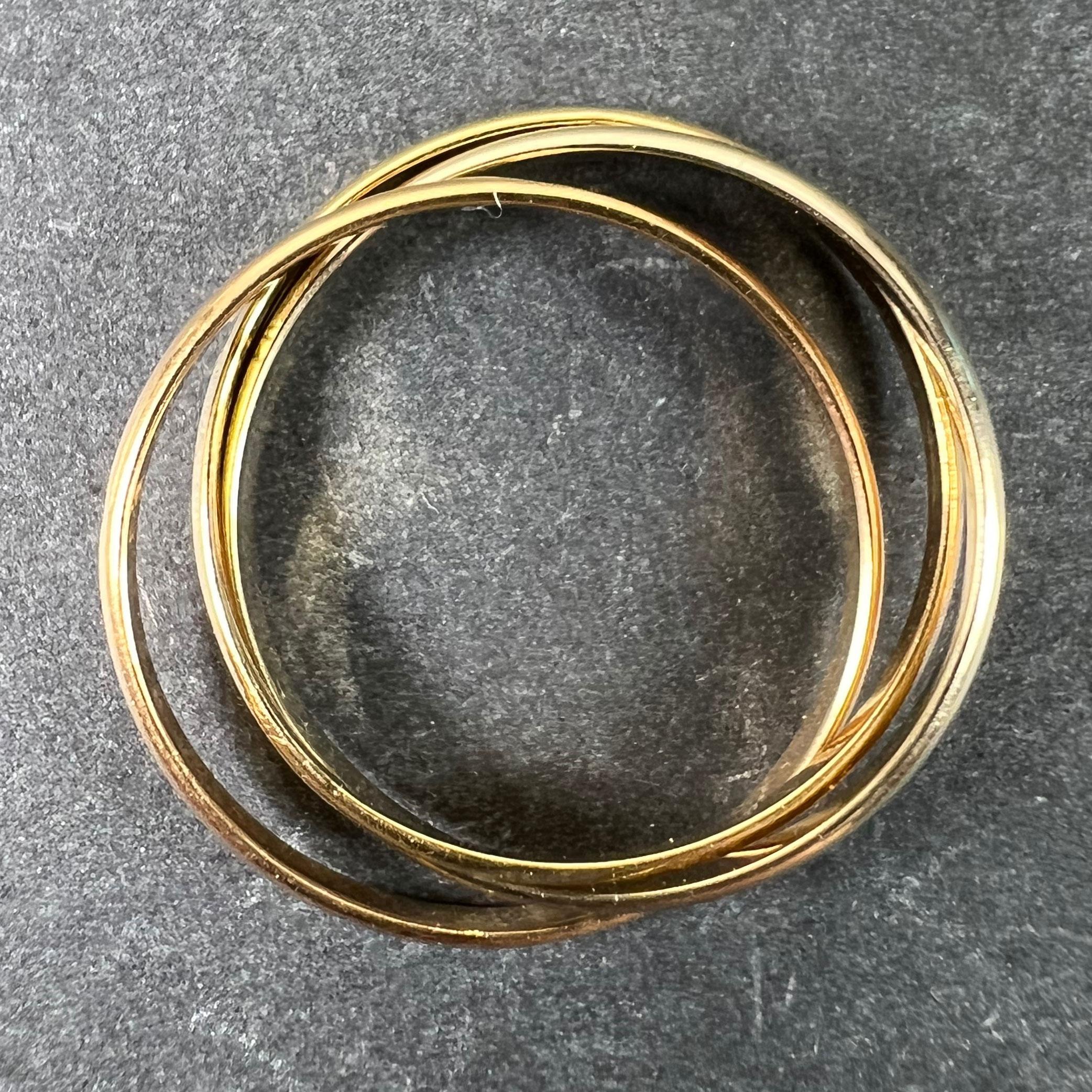 Anillo francés vintage de oro de 18 quilates (18K), diseñado como tres bandas entrelazadas de oro blanco, oro rosa y oro amarillo, al estilo de las alianzas trinitarias o rusas. Estampado con la marca del águila para oro de 18 quilates y fabricación