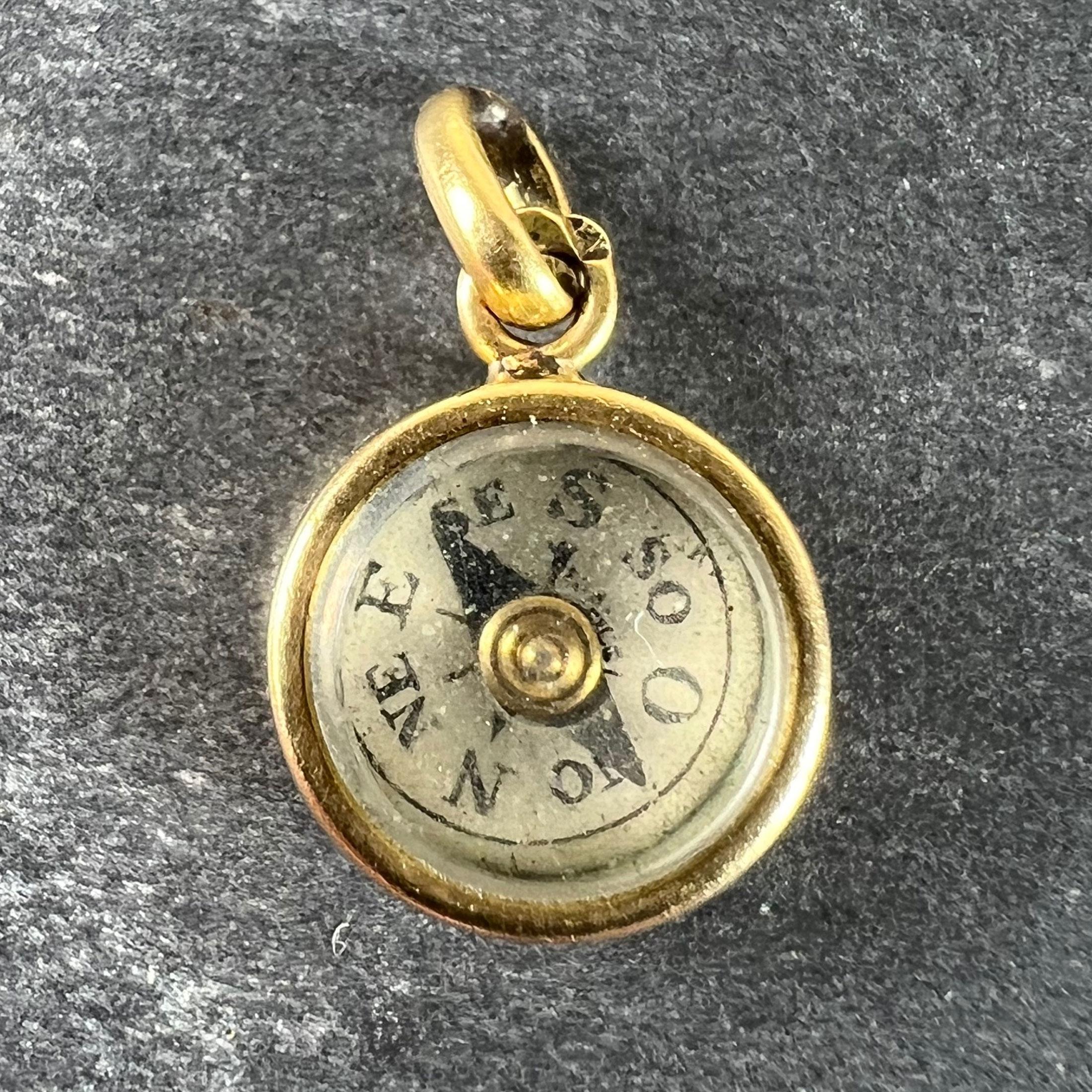 A French 18 karat (18K) yellow gold charm pendant designed as a compass with a spinning magnetic arrow. The directions are in French, so West is represented by the letter O. The dial marked 'France' to the centre. Stamped with the eagles head for