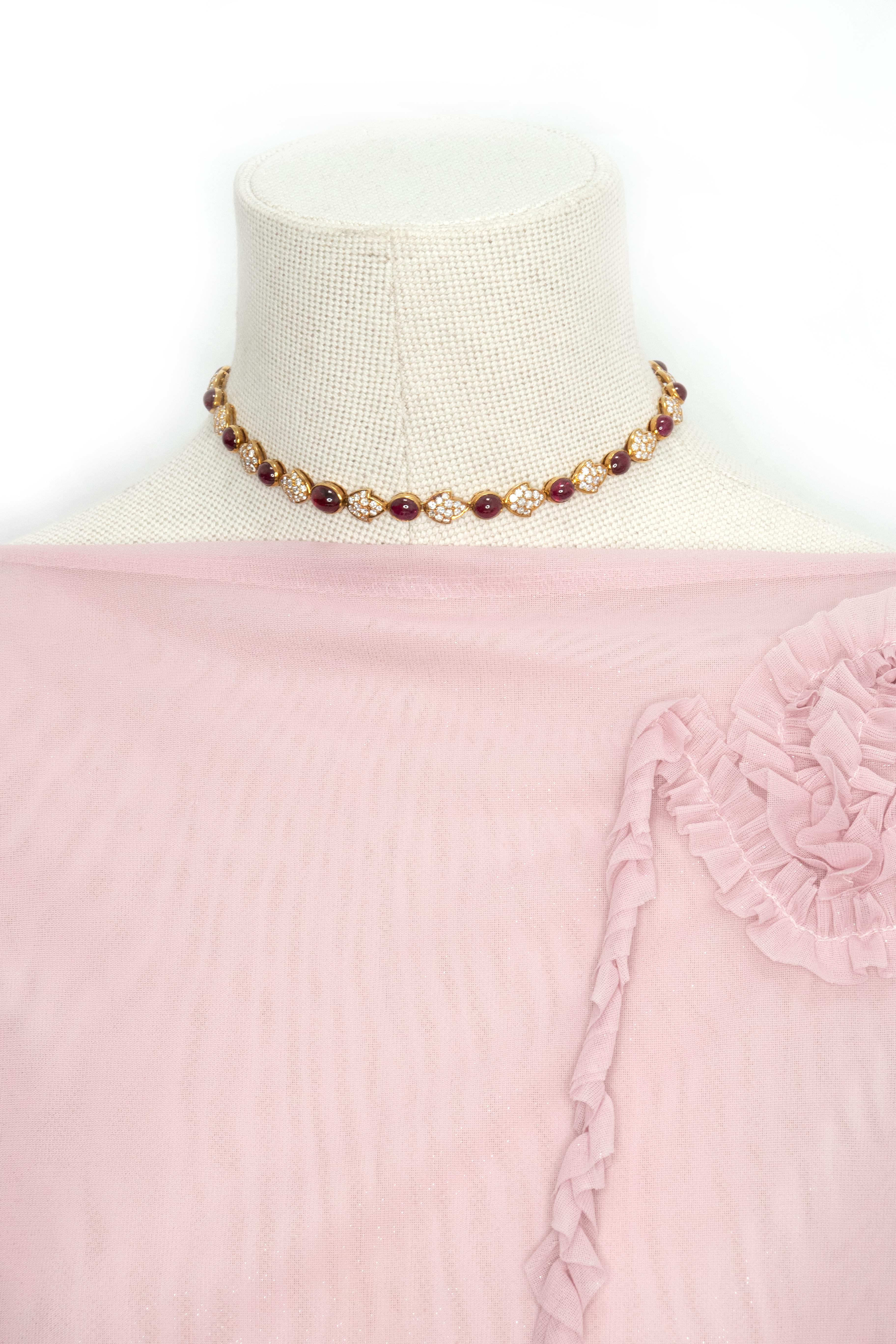 Elegant et sophistiqué, ce superbe collier ras de cou français est réalisé en or jaune 18 carats et présente un captivant motif alterné de rubis cabochons rouges et de feuilles de diamants serties en pavé. Le collier est serti d'environ 22,00 carats