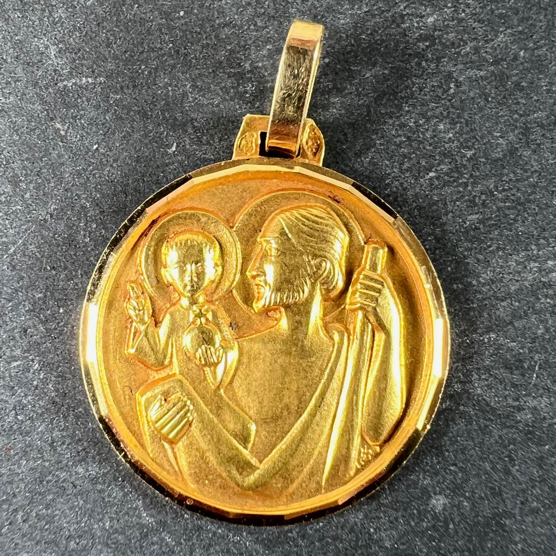Un ciondolo vintage French in oro giallo 18 carati (18K) disegnato come una medaglia religiosa rotonda raffigurante San Cristoforo che porta in braccio il Cristo bambino. Firmato JB, timbrato con la testa dell'aquila per l'oro a 18 carati e la
