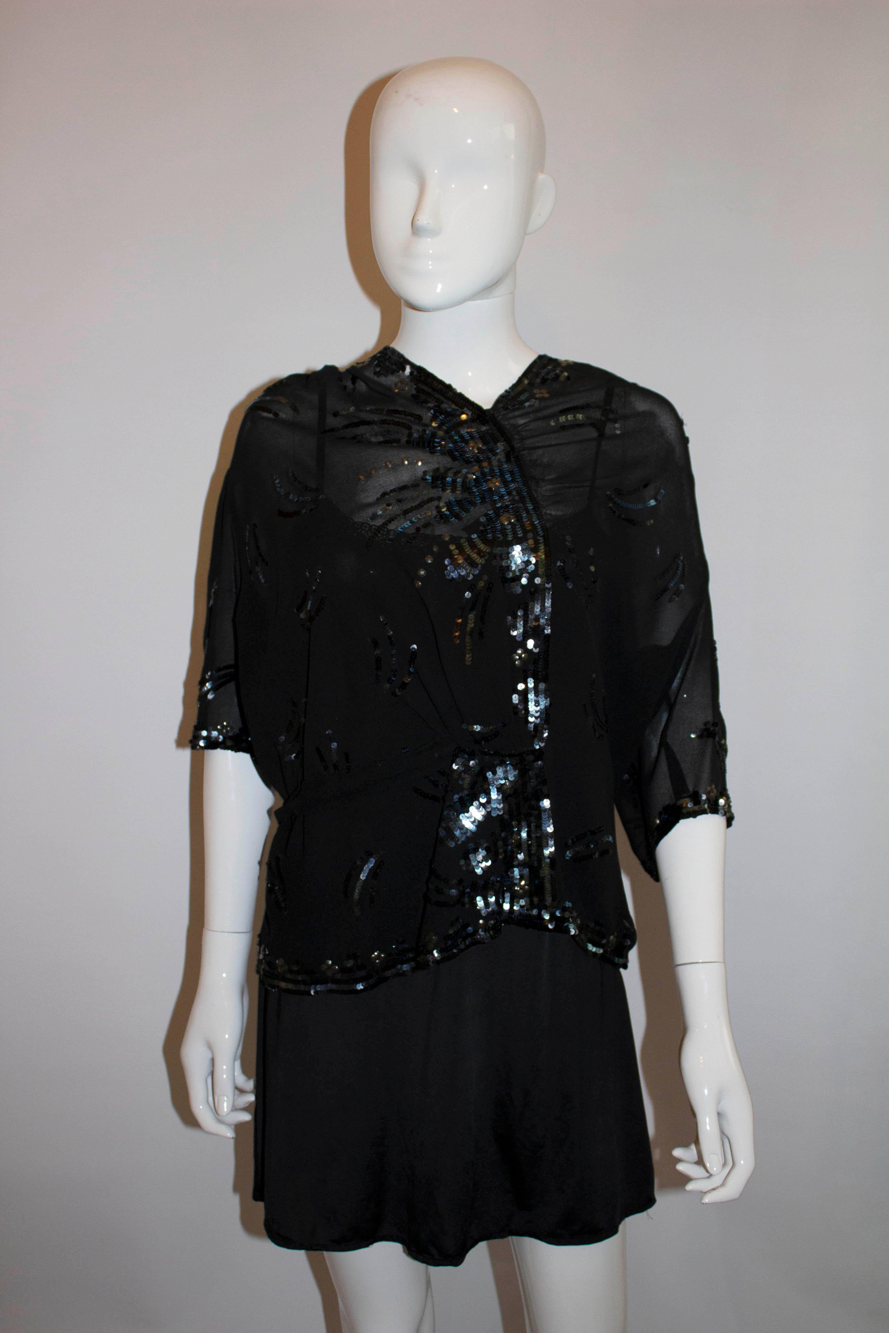 A chic vintage top from the 1940s. In black crepe with sequin detail, the top has gathering on the shoulder with a wrap over front and popper opening at the side and front. It has decoration on the front and back. 
Made in France . Measurements: