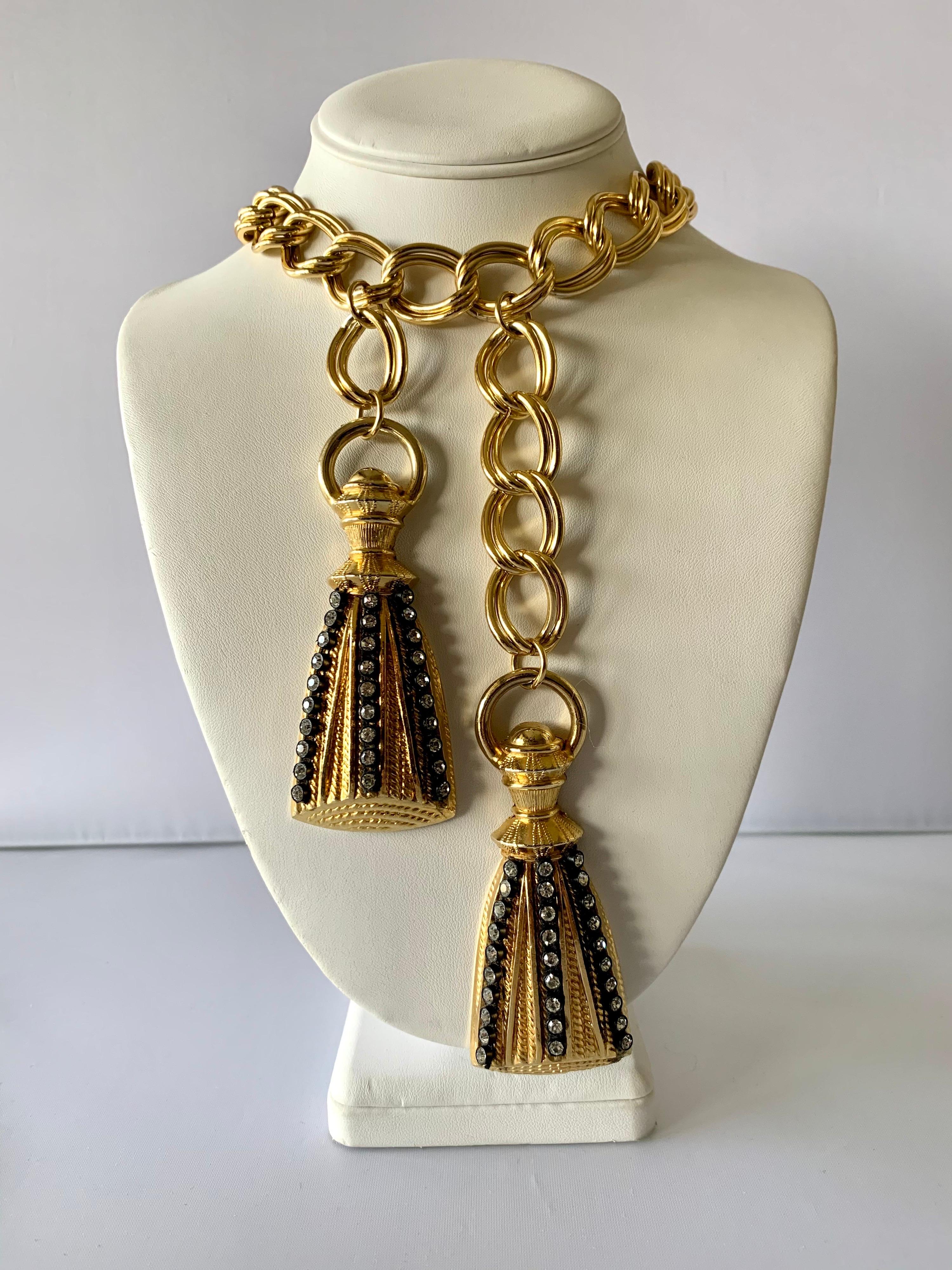 New old stock French gilt-metal tassel versatile necklace featuring a thick gold link chain which is accented by two large cast metal tassels adorned with black enamel and large Swarovski diamante rhinestones. The necklace can also be worn as a belt