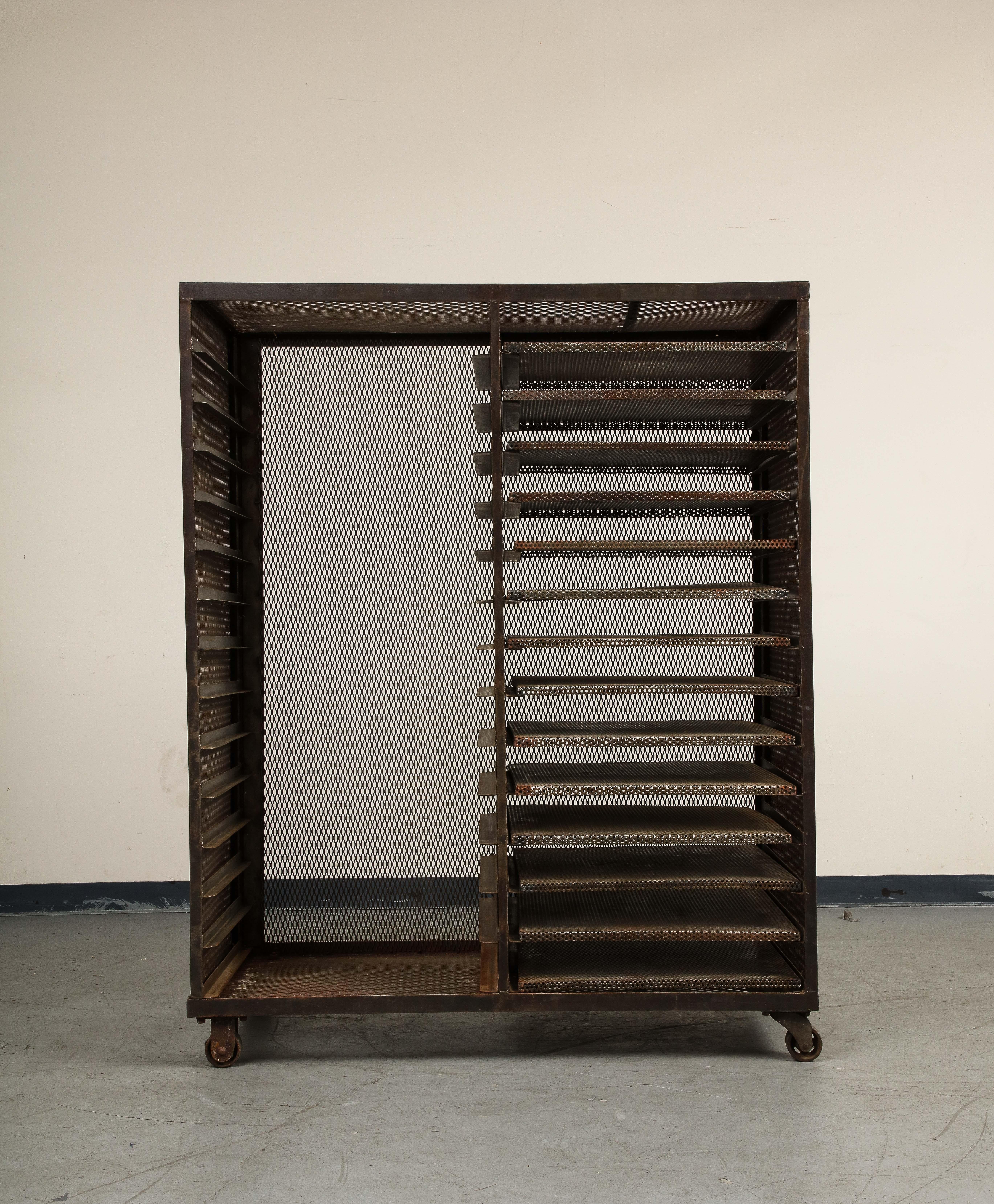 Vintage French 20th Century industrial style baker's rack or etagere on casters, entirely made of perforated steel. Shelves can be moved from either side, fixed heights are symmetrical.