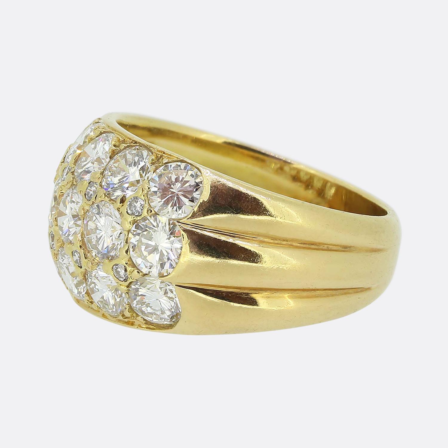 Here we have a fabulous cluster ring. This vintage piece was crafted in France from a rich 18ct yellow gold and showcases a pair of wide ribbed shoulders flanking a centralised cluster at the face formed of three rows of bright white round brilliant