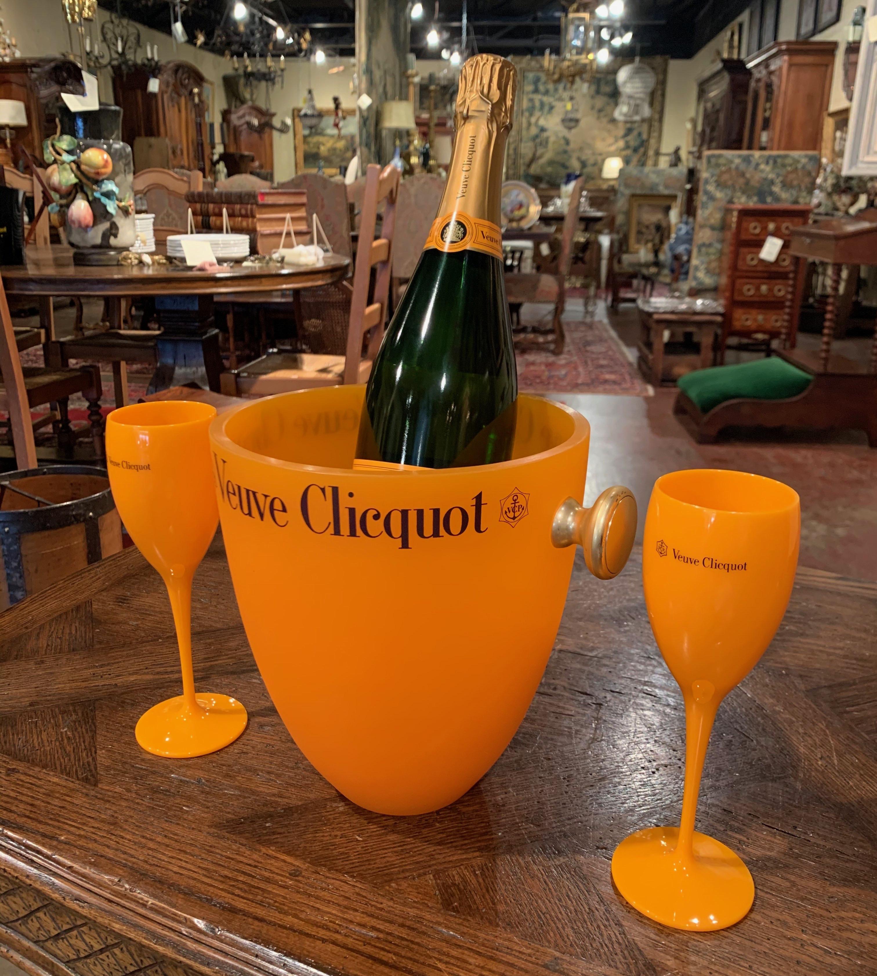 Decorate a wet bar with this elegant champagne bucket with two matching glasses; crafted in France circa 1980 by the iconic House of Veuve Clicquot, the acrylic cooler with side handle is decorated around the rim with the company's insignia as well