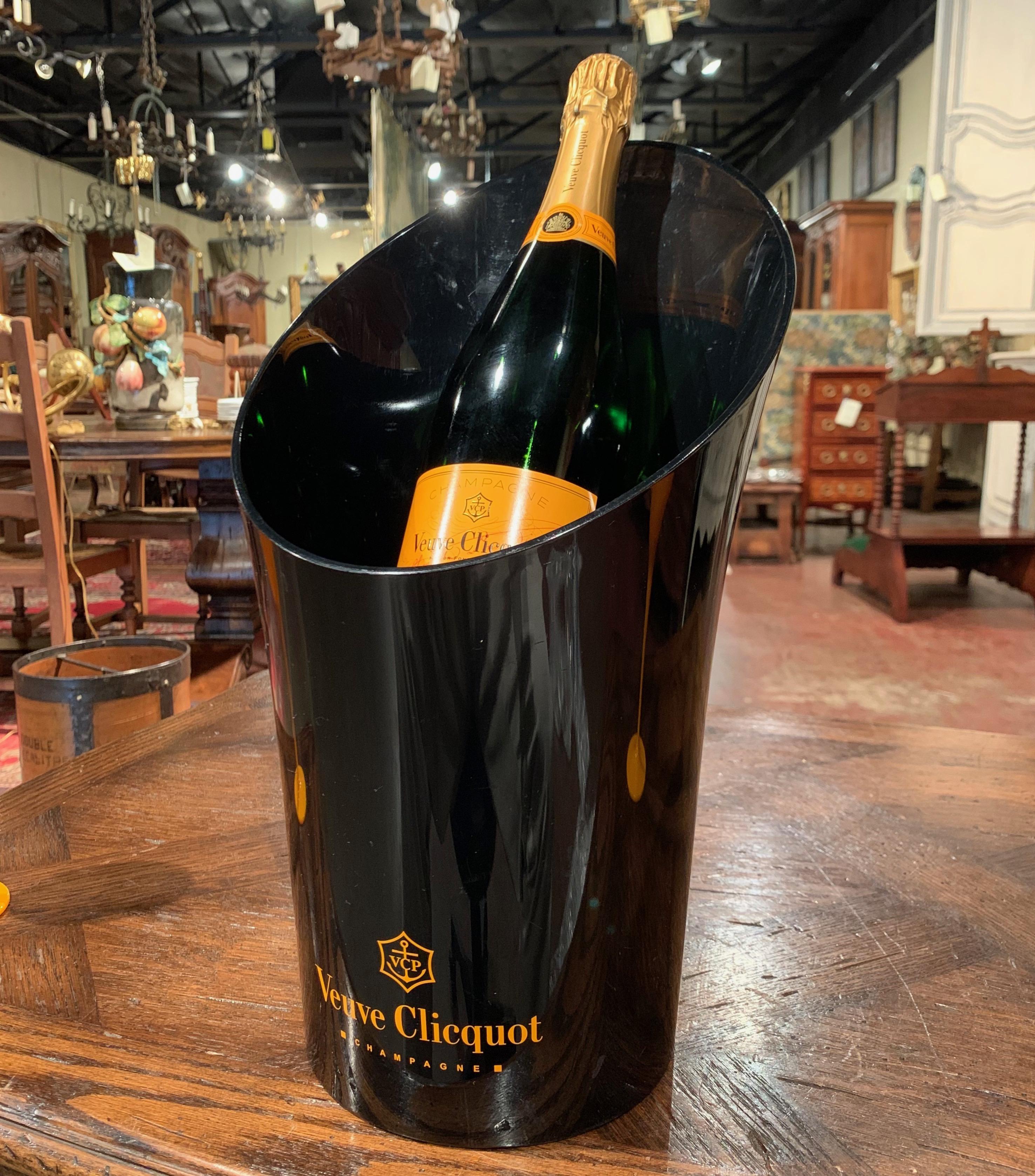 Decorate a wet bar with this elegant magnum champagne bucket with two matching glasses; crafted in France circa 1980 by the iconic House of Veuve Clicquot, the acrylic cooler is black and is decorated with the company's insignia. The bucket and the