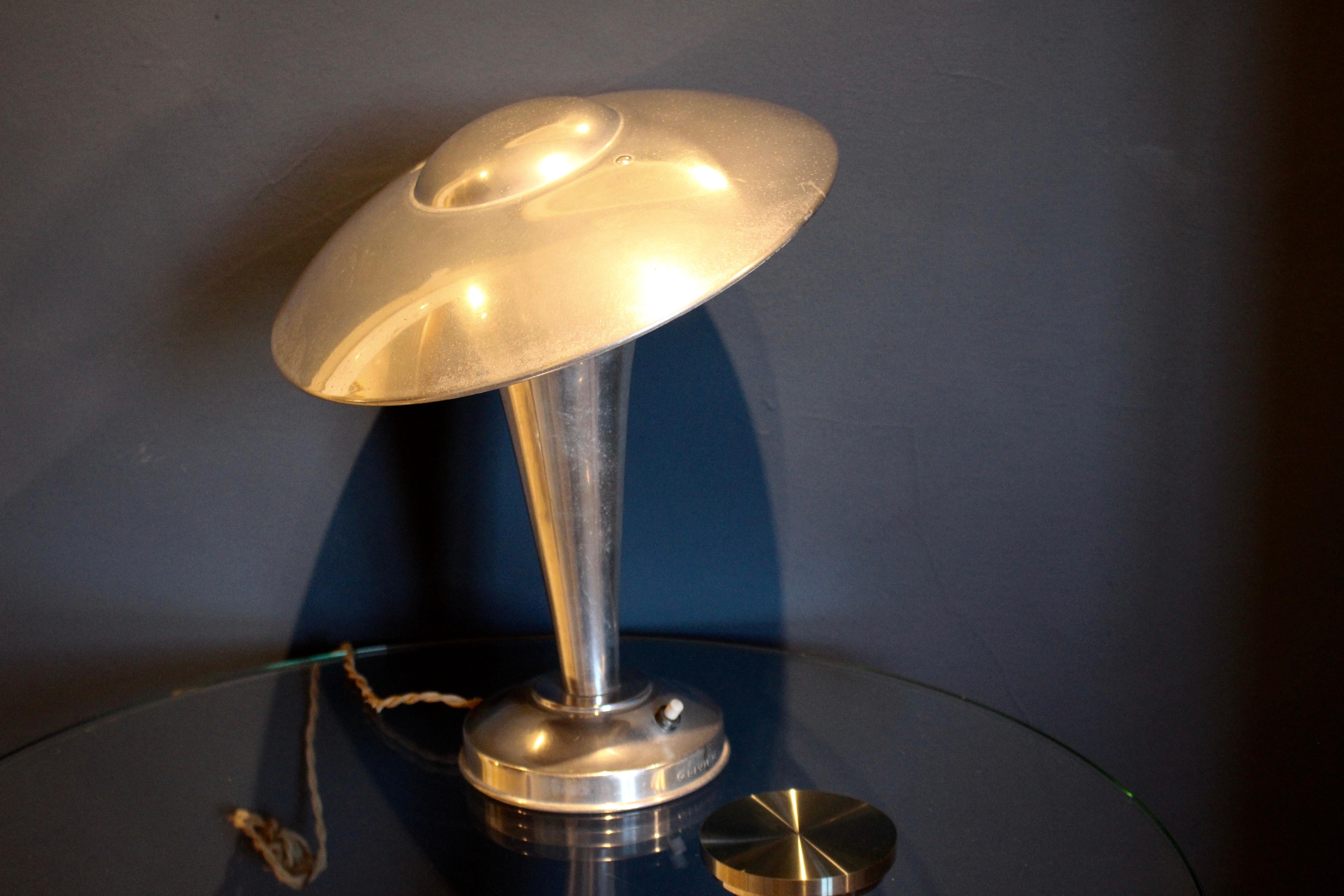 A lovely vintage aluminum lamp by Olivier. The adjustable saucer shade above a tapered cylindrical column and standing on a circular base. Push button switch. This light will be easy to rewire for the USA so we will leave the light with its original