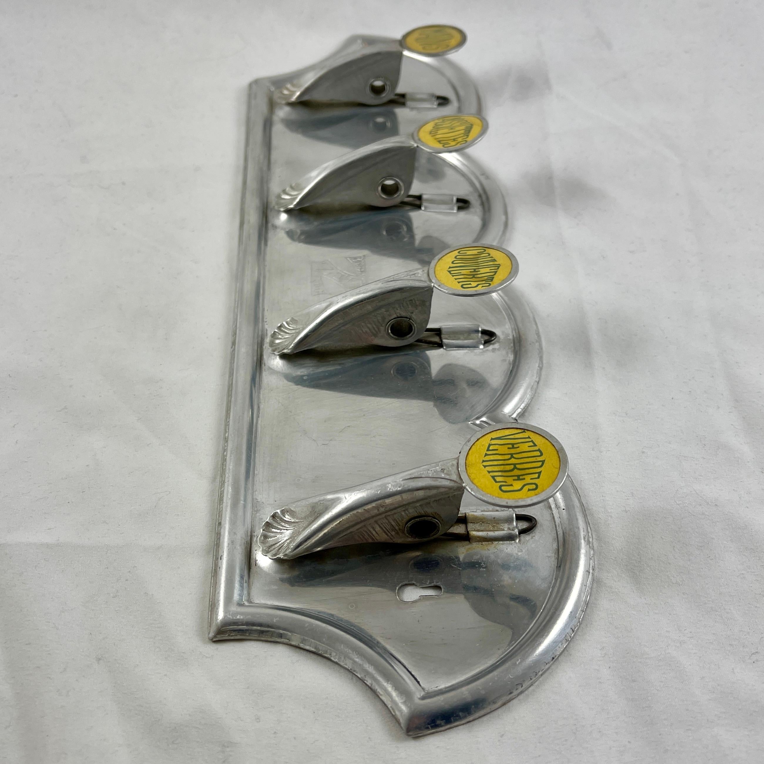 From the 1950s, a French kitchen dishcloth rack with spring loaded hooks for holding four towels, each marked for its own purpose.

Made of a shiny pressed aluminum, each holder showing a yellow and black printed label sealed under a heavy clear