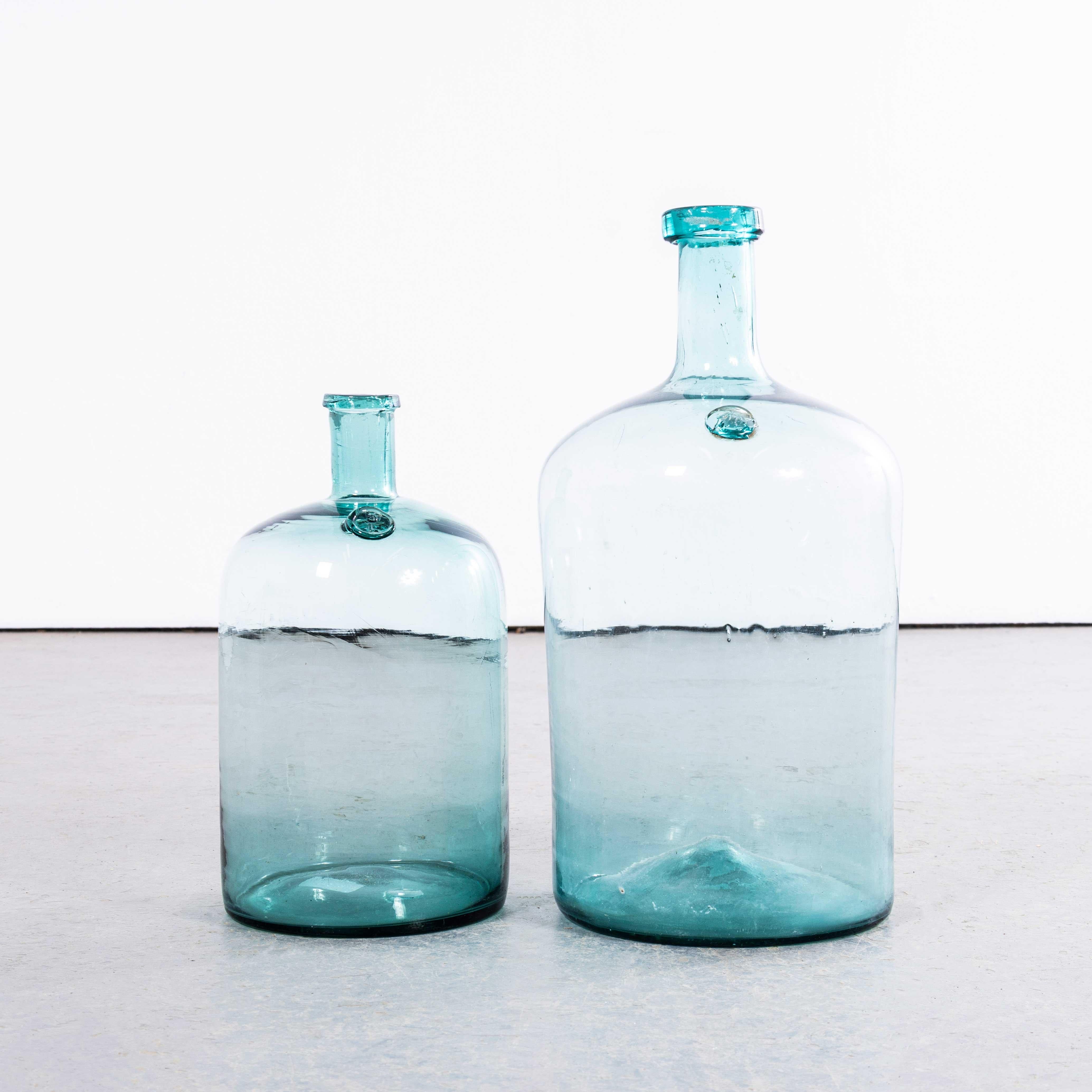 Damigiane francesi d'epoca in vetro acquatico - Coppia. 

Una coppia di damigiane in vetro soffiato a bocca utilizzate come contenitori tradizionali principalmente per la conservazione e il trasporto del vino. Queste damigiane sono state pulite con