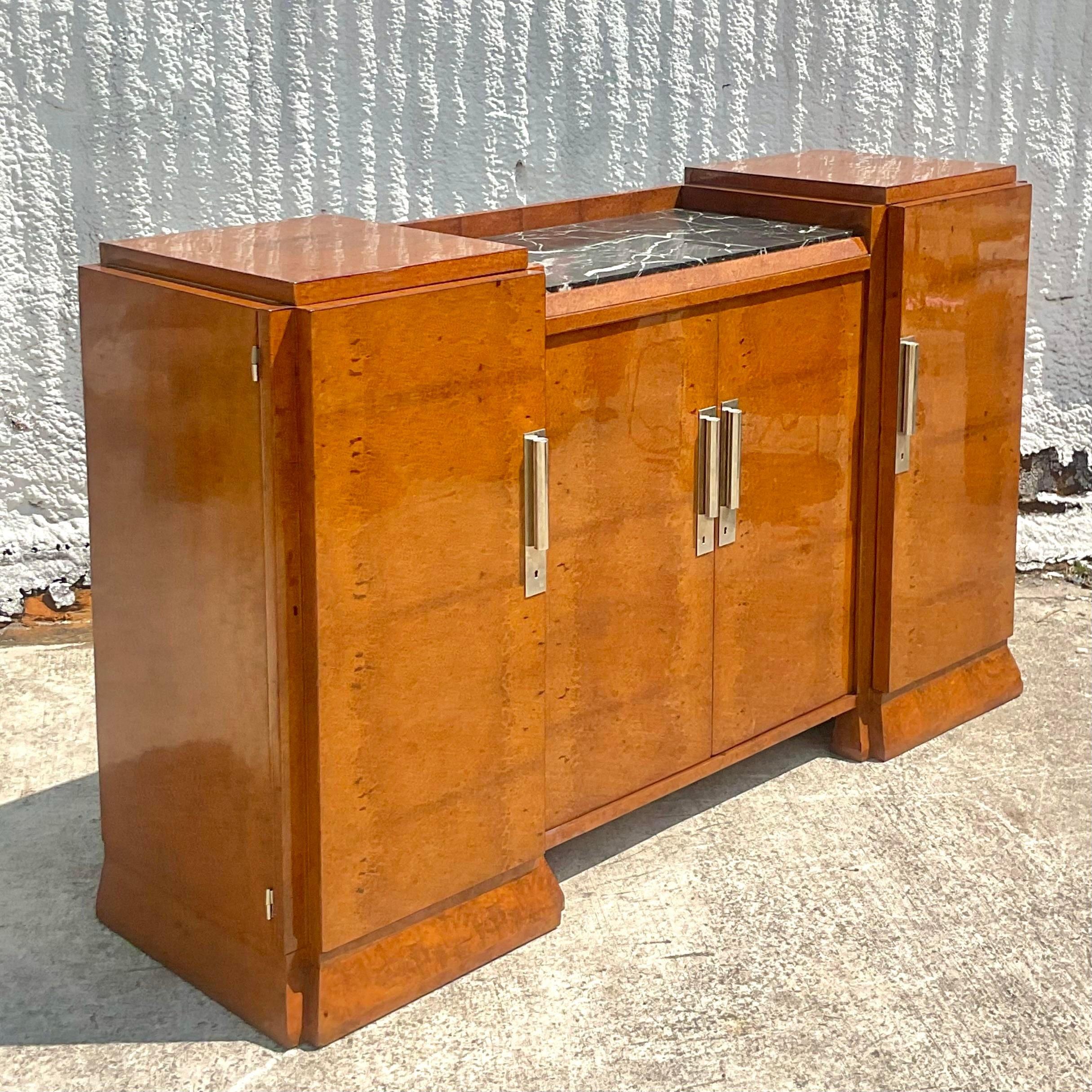 An exceptional vintage French Art Deco sideboard. Beautiful burl wood cabinet with black marble panel on top. Chic cylindrical hardware. A spectacular piece. Acquired from a Palm Beach estate.