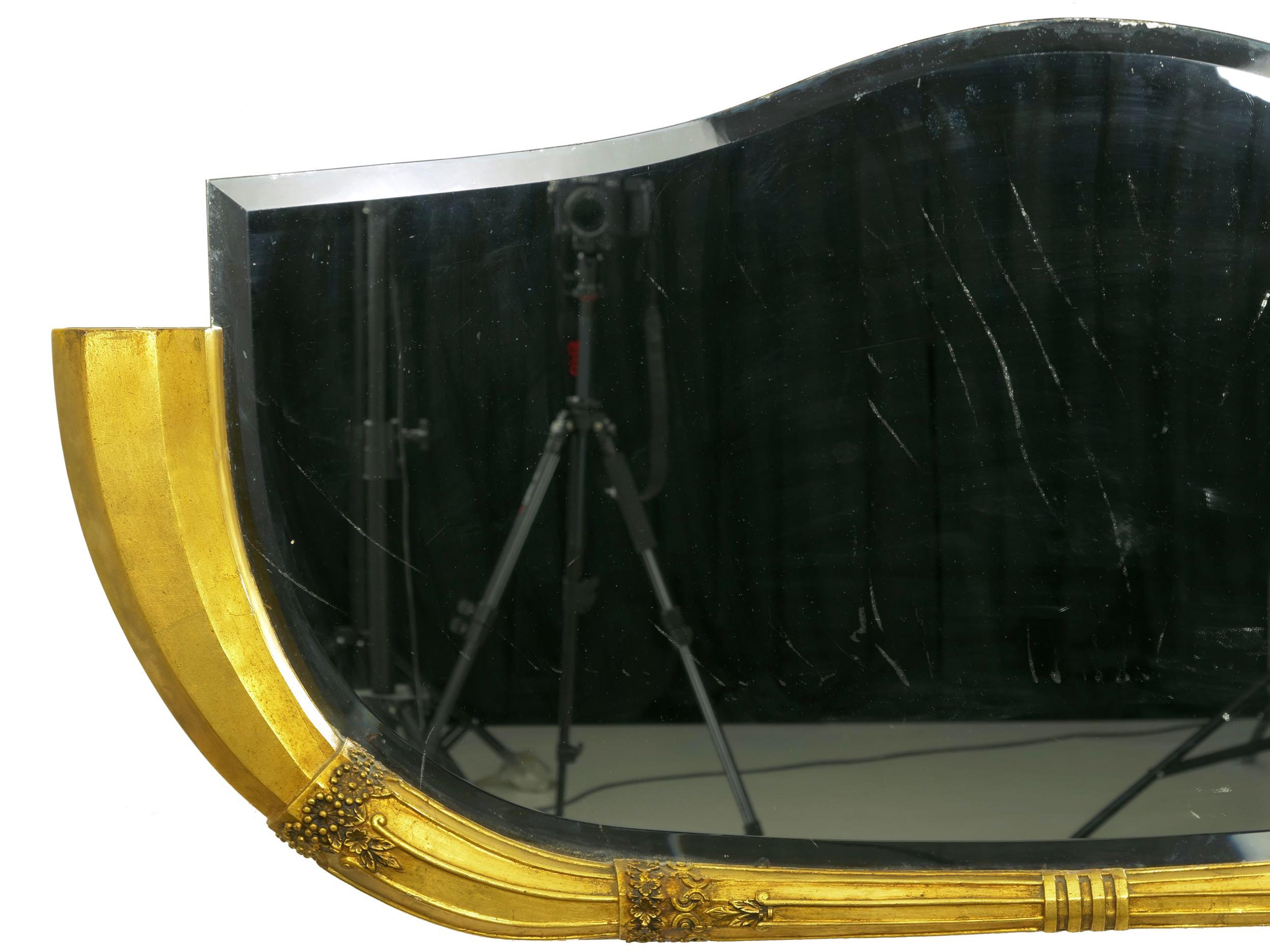 A superb and unusual Art Deco wall mirror from the second quarter of the 20th century, it is a piece intended primarily for placement over the fireplace mantel. The stylized trumpet form of the frame is a symmetrical design that swells from a fluted