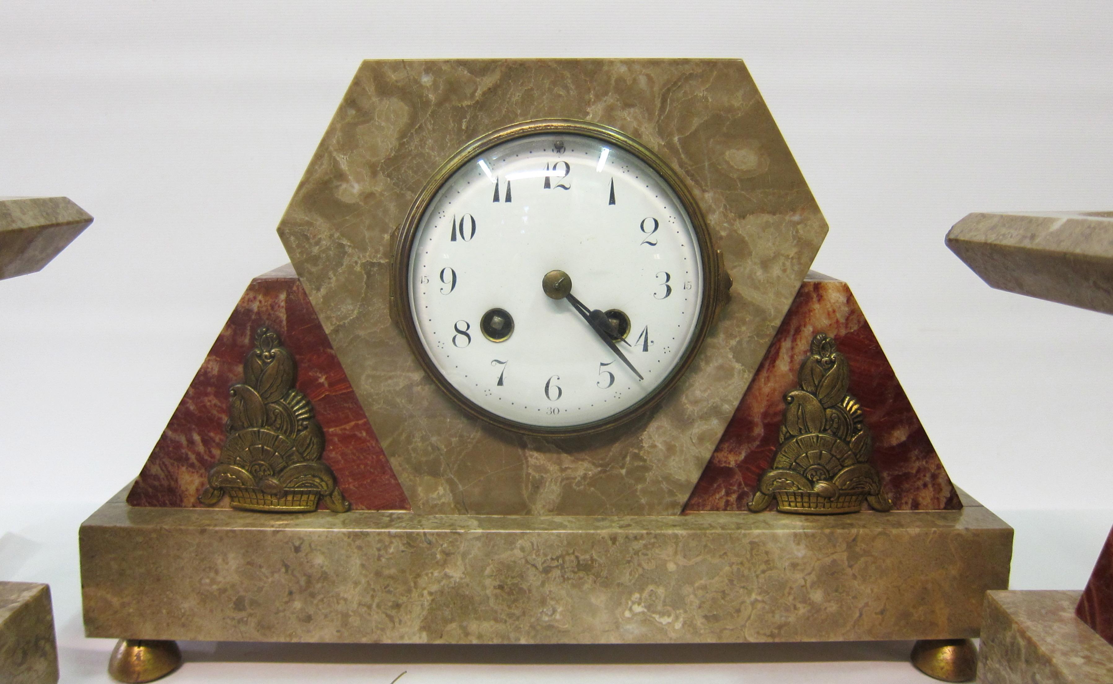 A vintage Art Deco clock set, circa 1930. The clock and matching accessories are accented with detailed bronze decorations that are mounted on triangular rouge marble shapes. This rouge marble together with contrasting sandalwood color marble forms