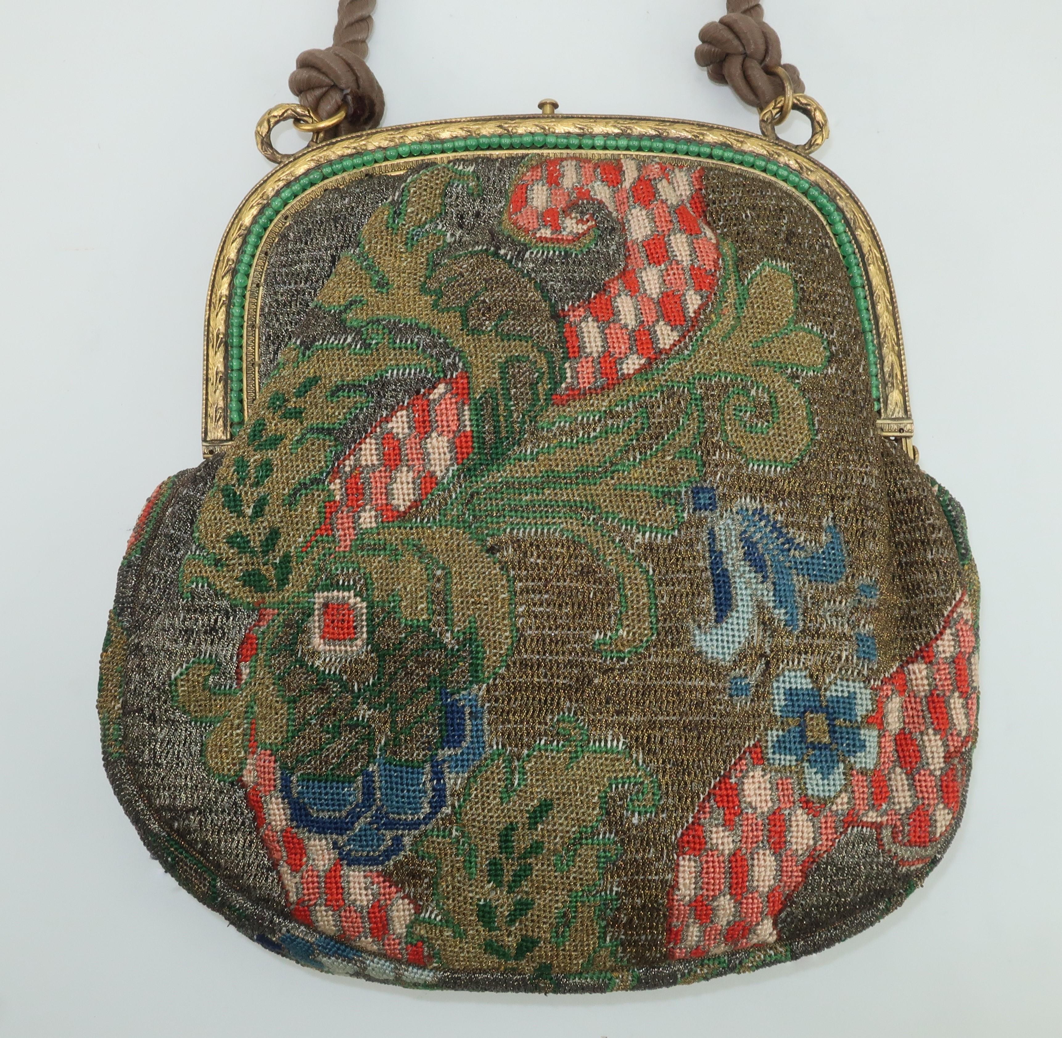 Early 20th Century French petit point handbag with an abstract Art Deco floral pattern in shades of pink, red, green, blue and brown uniquely embellished by bronze metallic threading.  The gilt metal frame has a laurel leaf design with emerald green