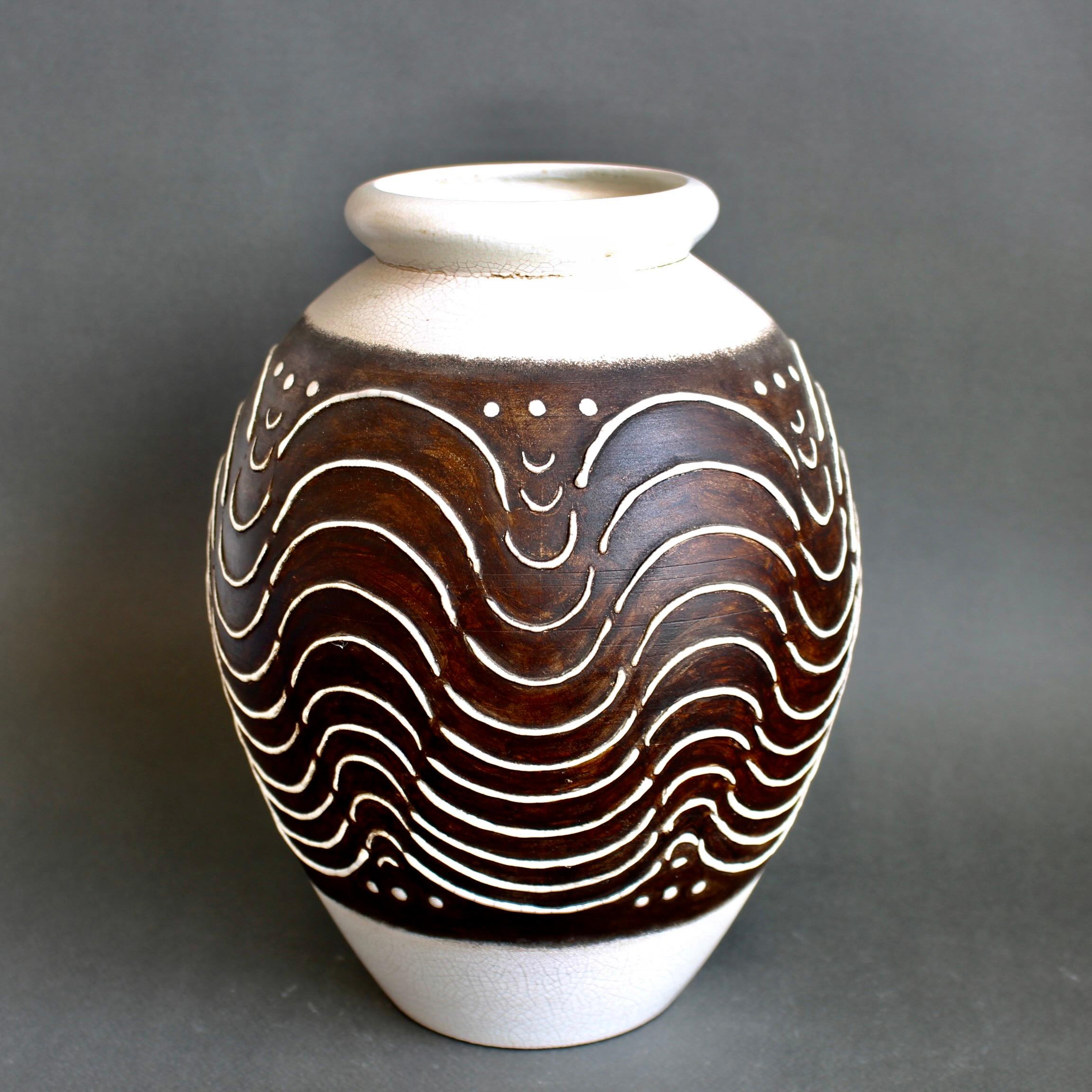 Französische Vase im Art-déco-Stil (ca. 1930-1950er Jahre). In der Art von Primavera oder Jean Besnard präsentiert diese entzückende Vase ein schönes, erhabenes Dekor in cremigem Weiß über einem ruhigen Schokoladenbraun. Der Rest des Körpers ist mit