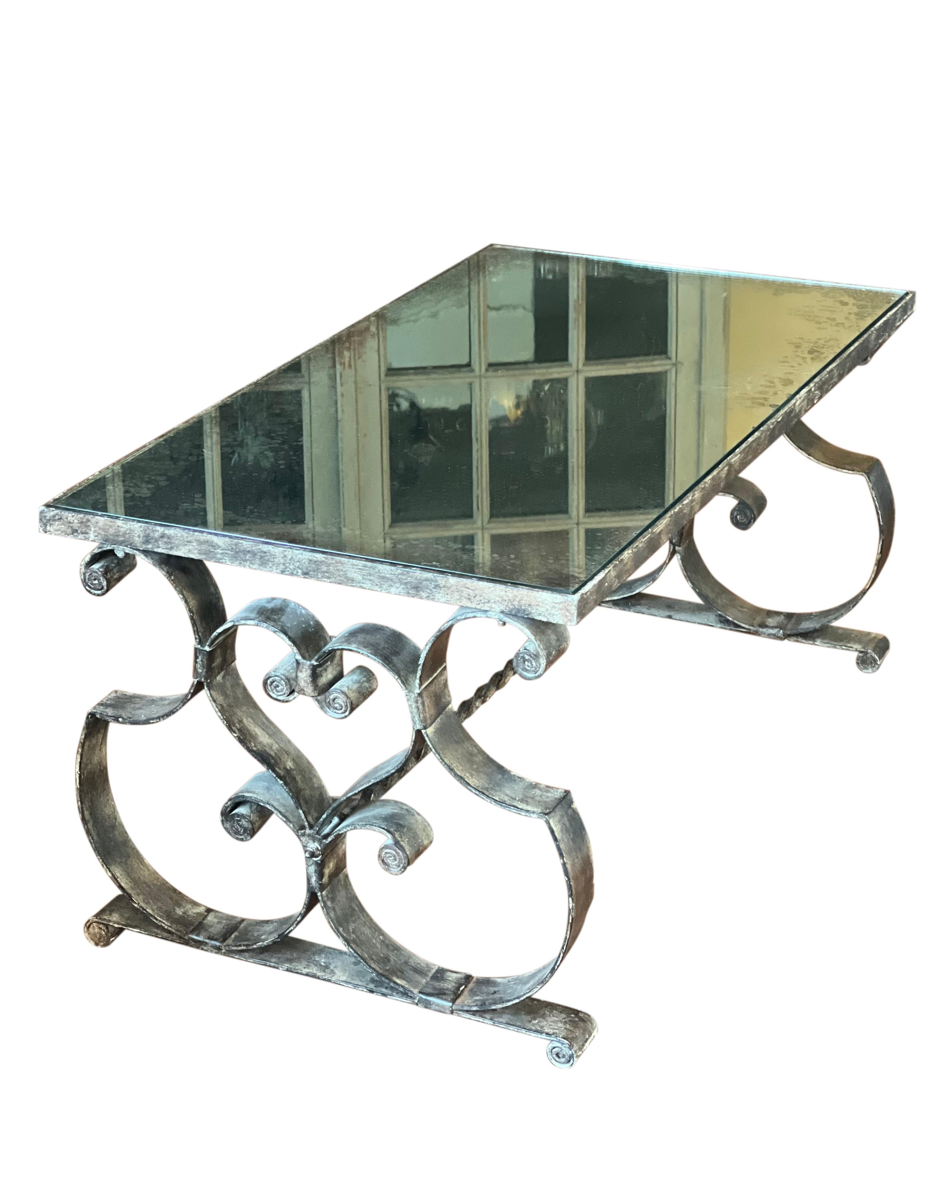 Exceptional French Art Deco wrought iron coffee table with antiqued mirror top, early 20th century.

The table's base features bold and graceful scroll work detail with an aged finish. The antiqued mirror top makes this beautiful table extra special.