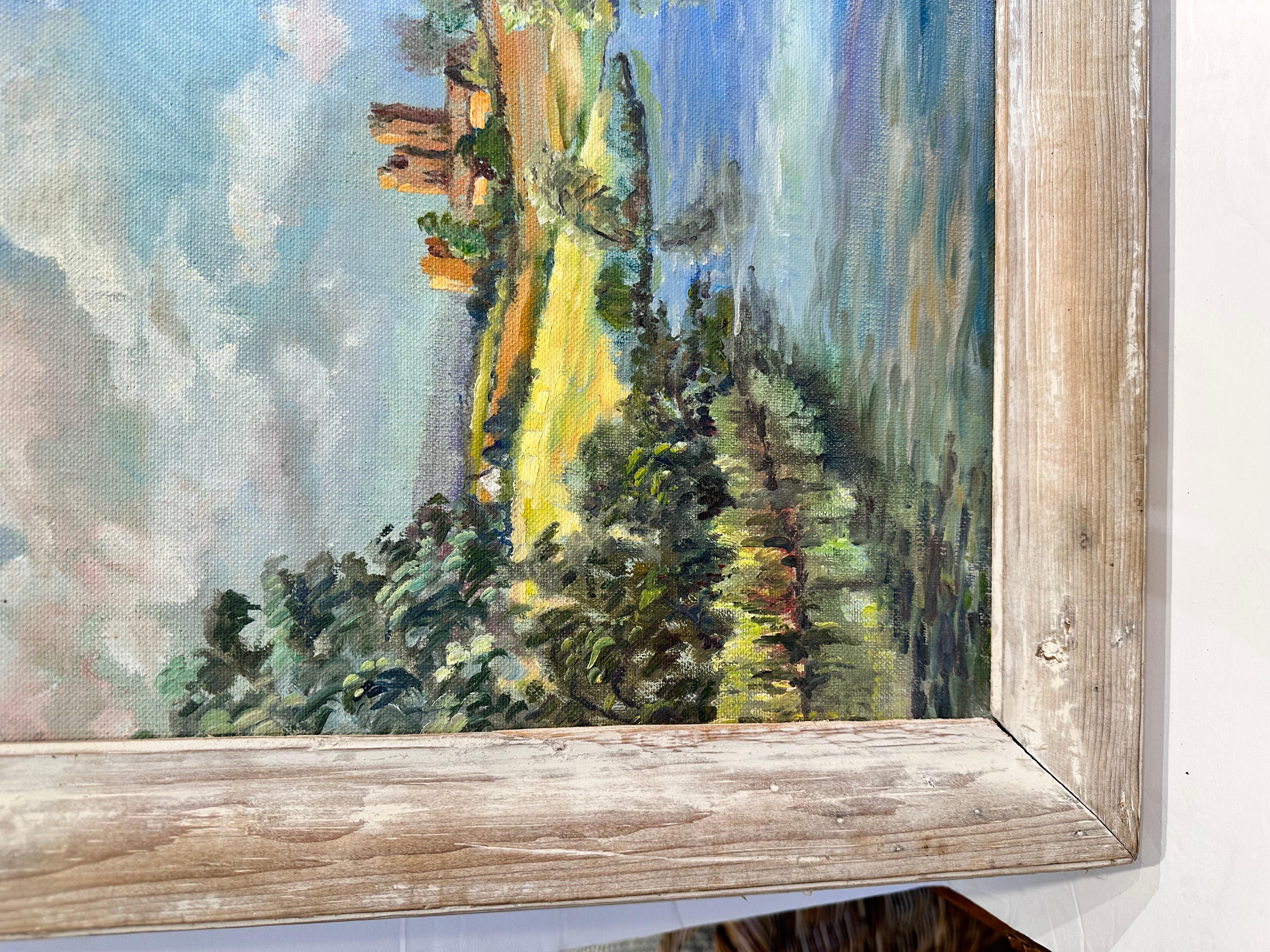 This is a beautiful antique French landscape! The color palette of this piece is light and vibrant with green and blue hues mixing with softer brown and yellow. In the forefront of the painting a river runs through the countryside and fades into the