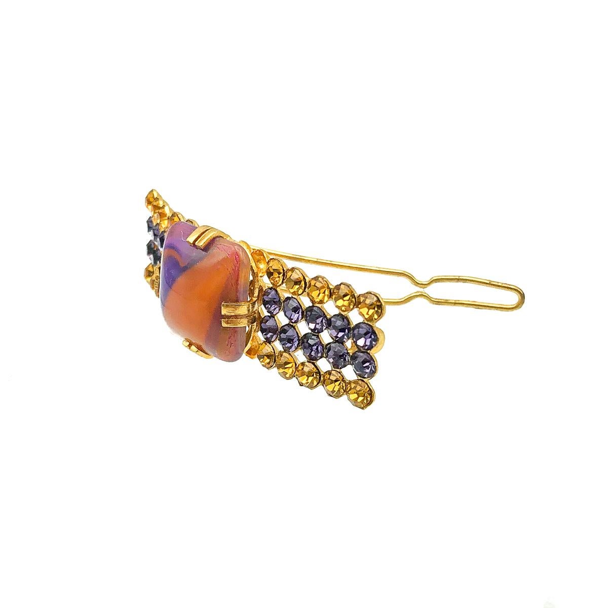 A Vintage French Hairslide. Featuring rich colours of gold and purple for a glorious contrast. Incorporating a large claw set, central art glass stone with gold and amethyst paste chatons sitting in four rows on either side. Set in gold plated