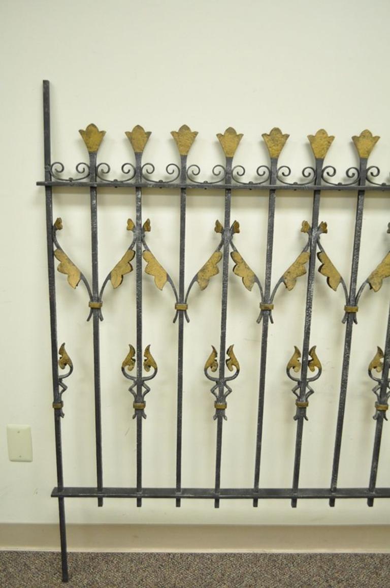 Ornate vintage Art Nouveau French style wrought iron gate. The piece is largely finished in black with gold gilt floral or ribbon motif. Though initially constructed as a portion of a fence, this piece would be excellent re-purposed for use as a
