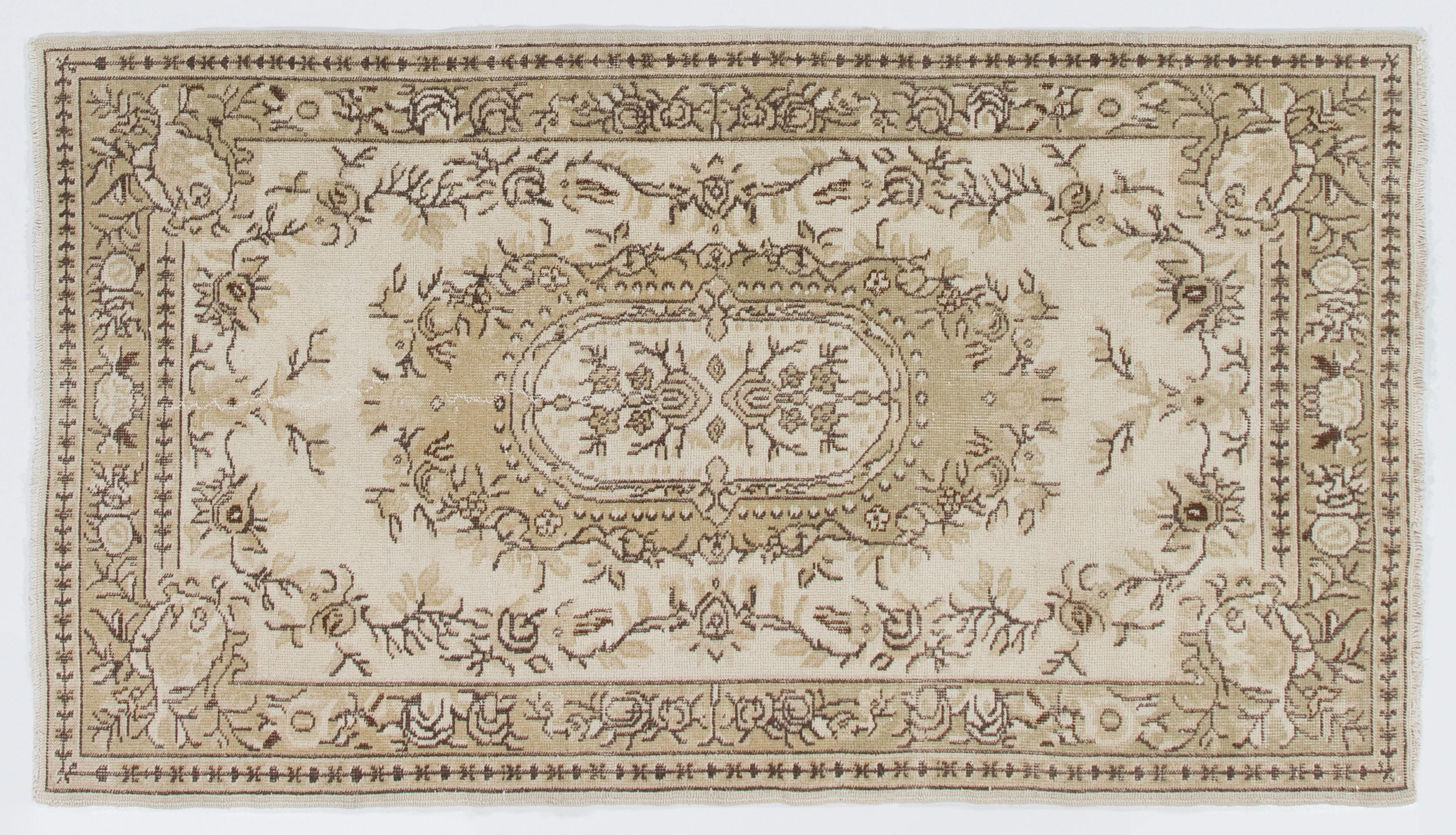 A hand-knotted 1960s Turkish rug with a French Aubusson design with low wool pile on cotton foundation. It features at its center a large floral cartouche in soft, light green that is encircled by a floral wreath against a light beige background.