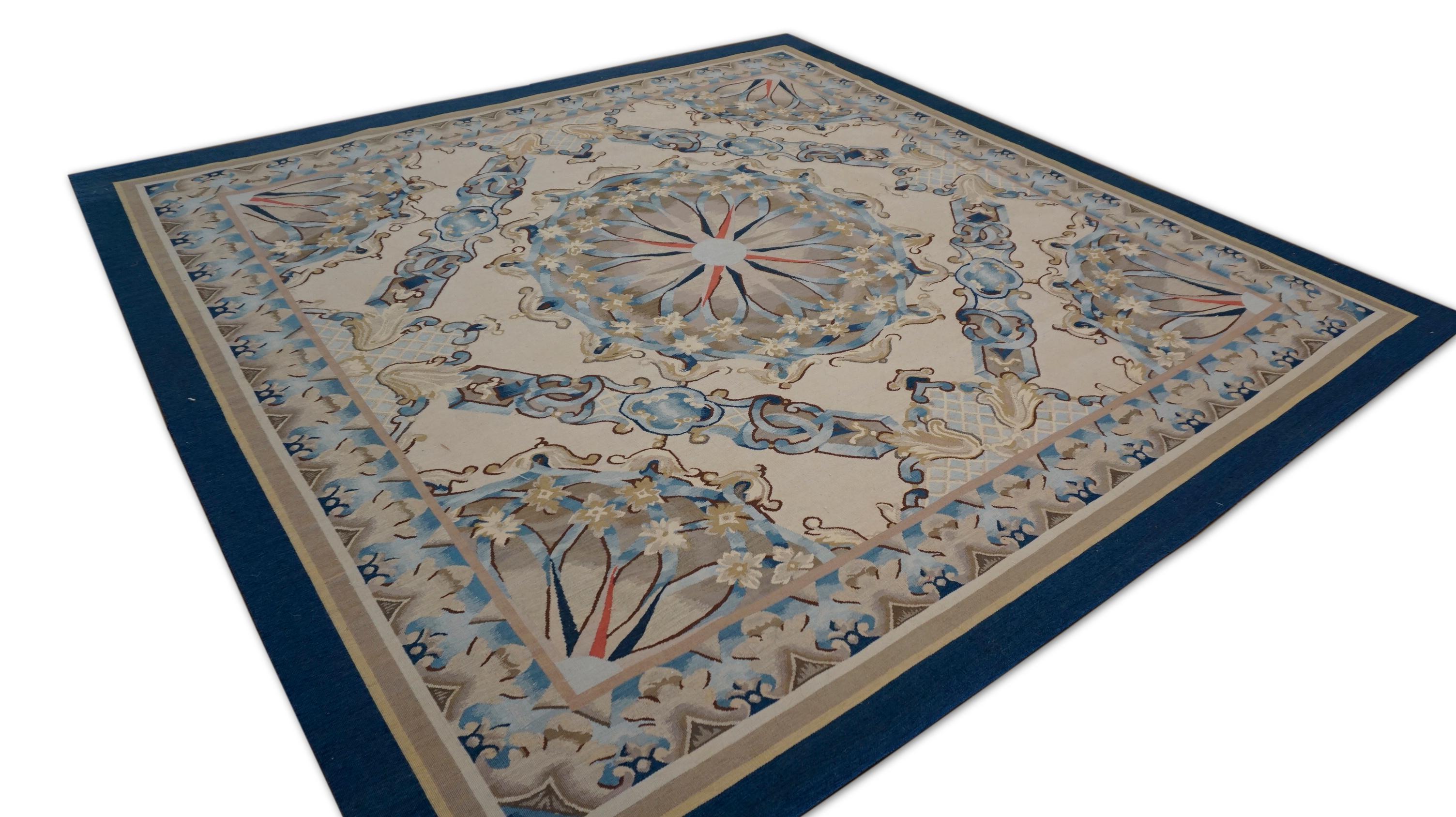 This sophisticated square wool rug is a masterfully woven example of Aubusson-style design, blending regal elegance with fine craftsmanship. The rug features a striking central floral medallion flanked by quarter medallions in each corner, all set