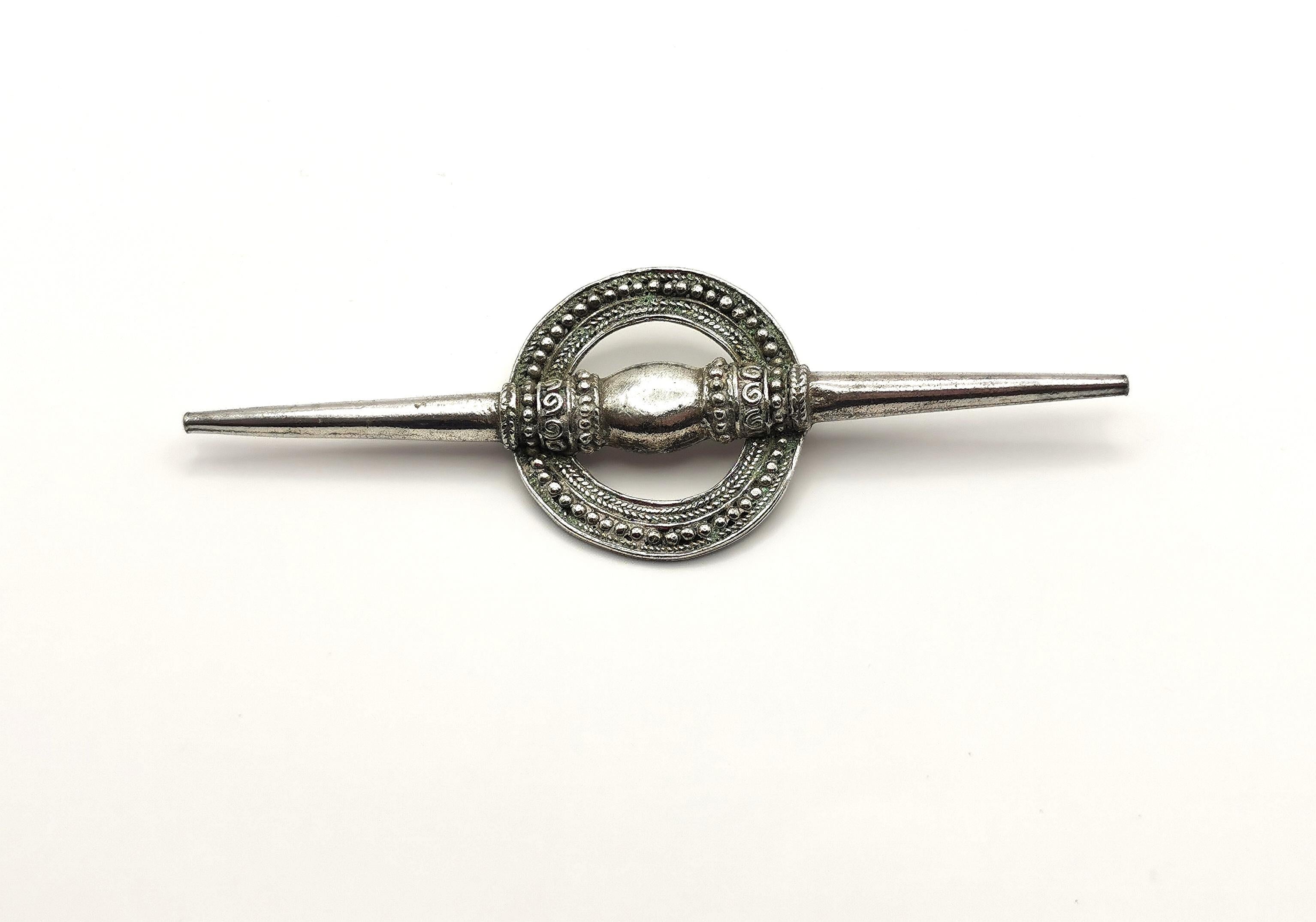 A wonderful vintage French designer brooch.

This is a very large sized white metal brooch, very Avant Garde with a Boho touch, it has a large pointed spear shaped bar running through a rustic engraved and embossed circle.

The brooch fastens with a