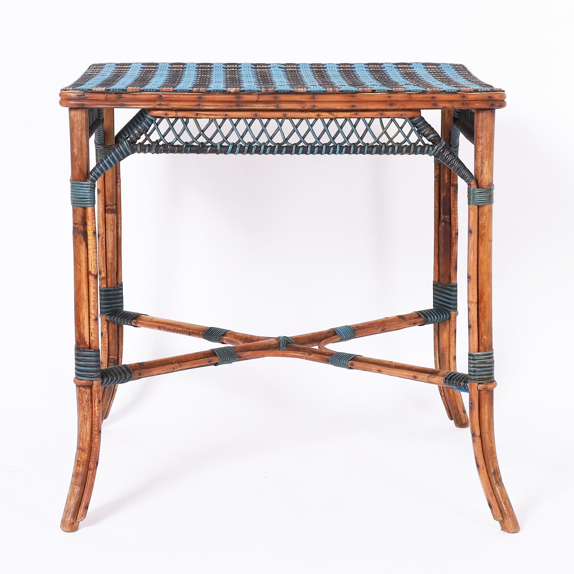 Table de transport française à plateau rectangulaire en roseau tressé décoré en bleu et noir sur une base en bambou avec des jupes en rotin décorées, des entretoises et des pieds évasés.