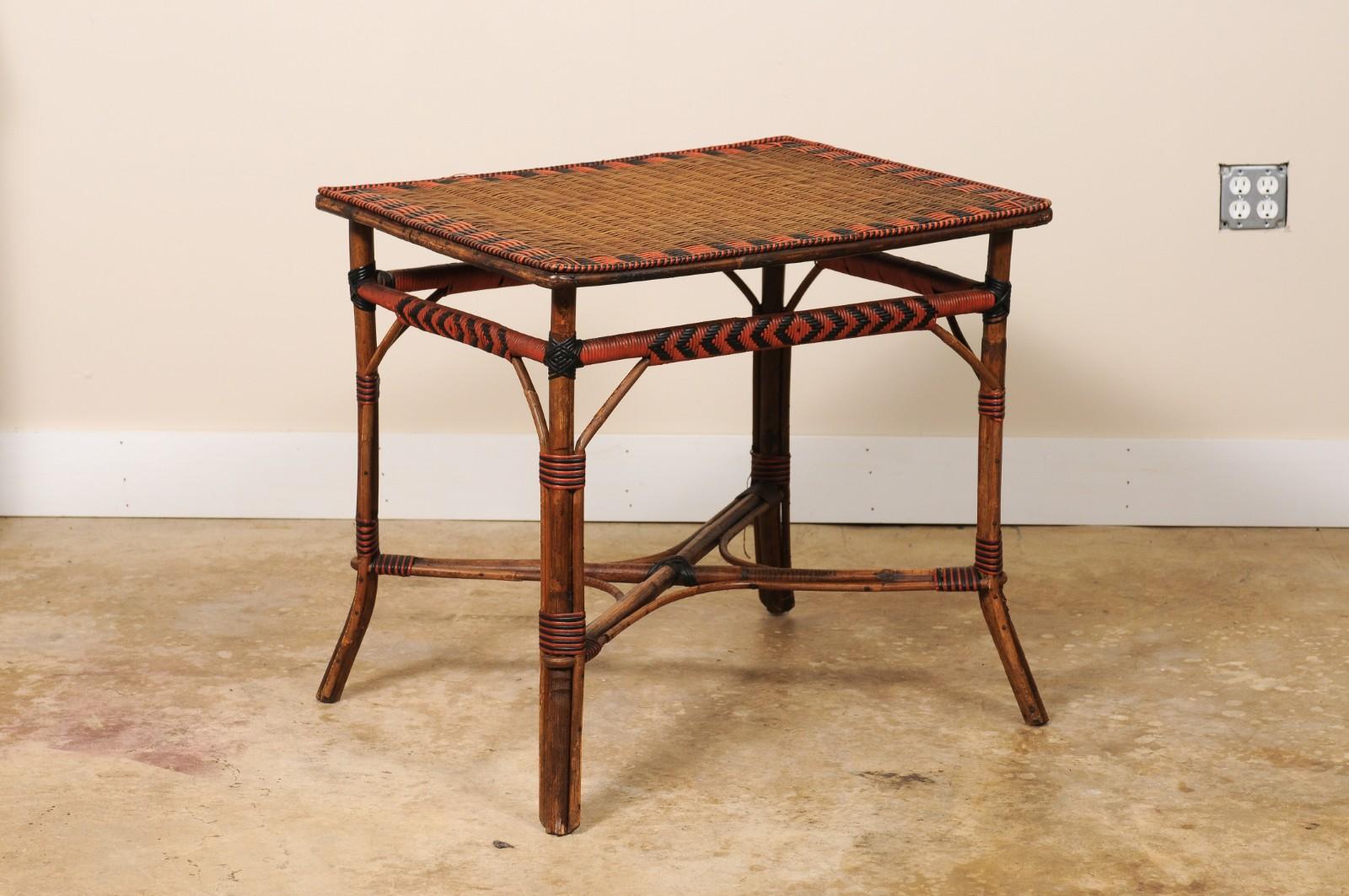 French table crafted with a rectangular top featuring woven reed paint decorated in red and black over a bamboo base with decorated rattan skirts, cross stretchers and splayed legs.

Purchased in the South of France