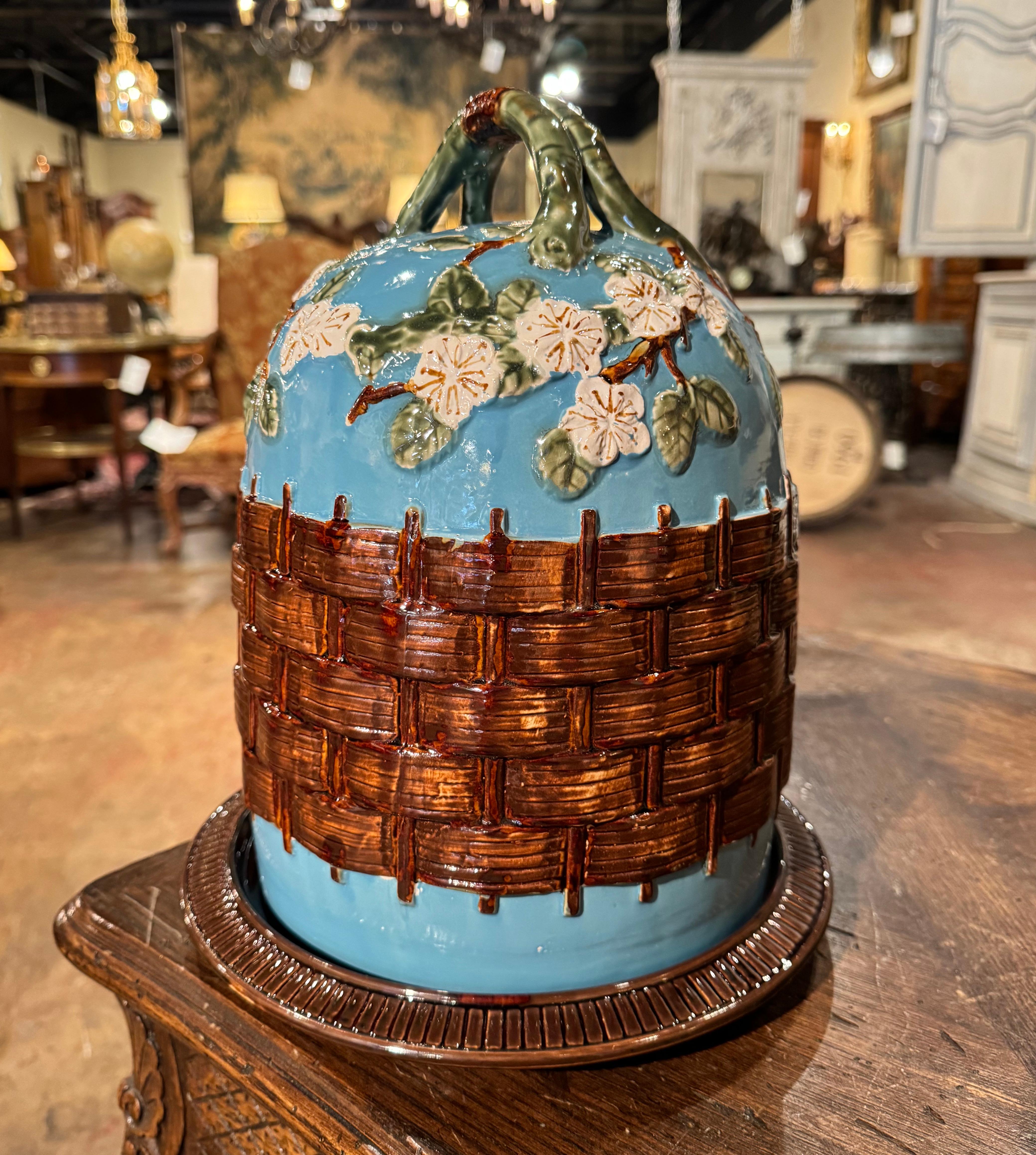 This colorful two-piece antique Majolica cheese dome was crafted in France, circa 1980. The piece includes a bottom circular platter decorated with stripe motifs, and the lid shaped as a dome features a double-tree branch top handle, and is