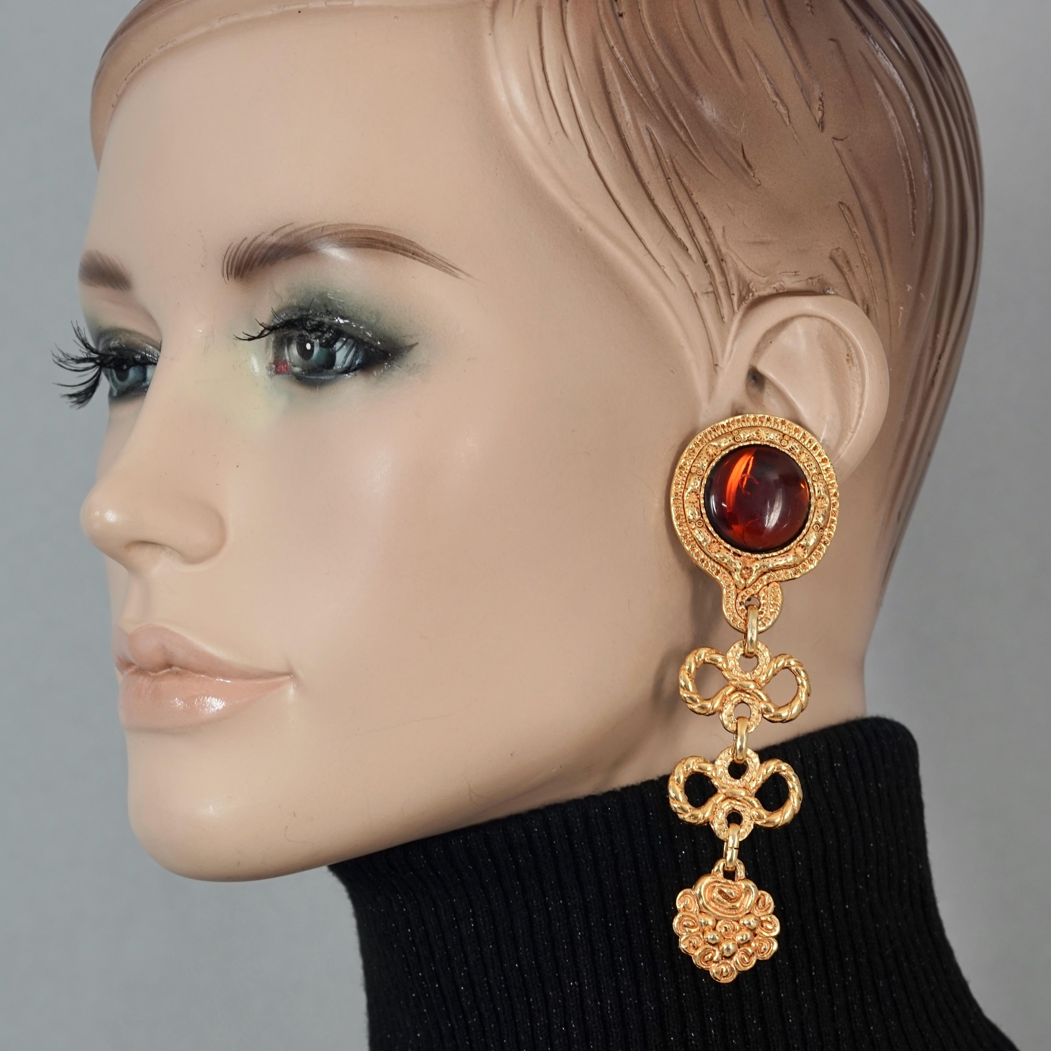 Vintage French Baroque Red Cabochon Tiered Bows Dangling Earrings

Measurements:
Height: 4.13 inches (10.5 cm)
Width: 1.29 inches (3.3 cm)
Weight per Earring: 21 grams

Features:
- French Baroque style earrings with red cabochon accent and tiered