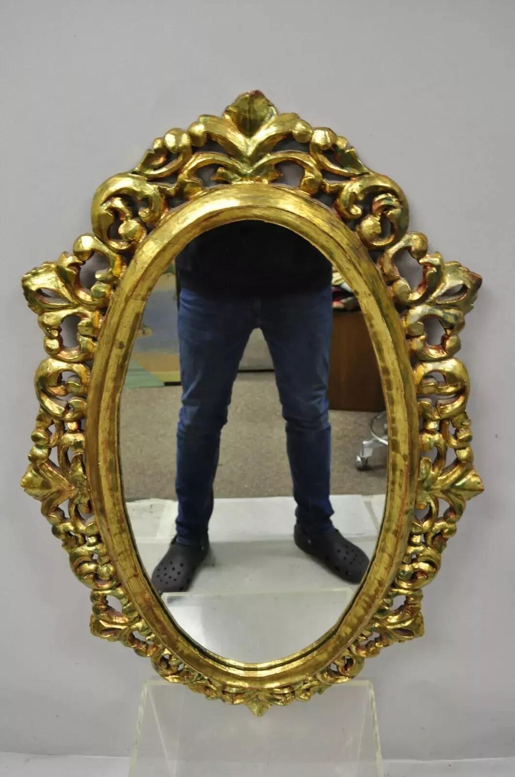 Specchio da parete ovale d'epoca in stile barocco francese, intagliato in oro e legno dorato. L'articolo presenta una finitura dorata, una cornice in legno massiccio, dettagli ben intagliati, grande stile e forma. La cornice in Wood sembra risalire