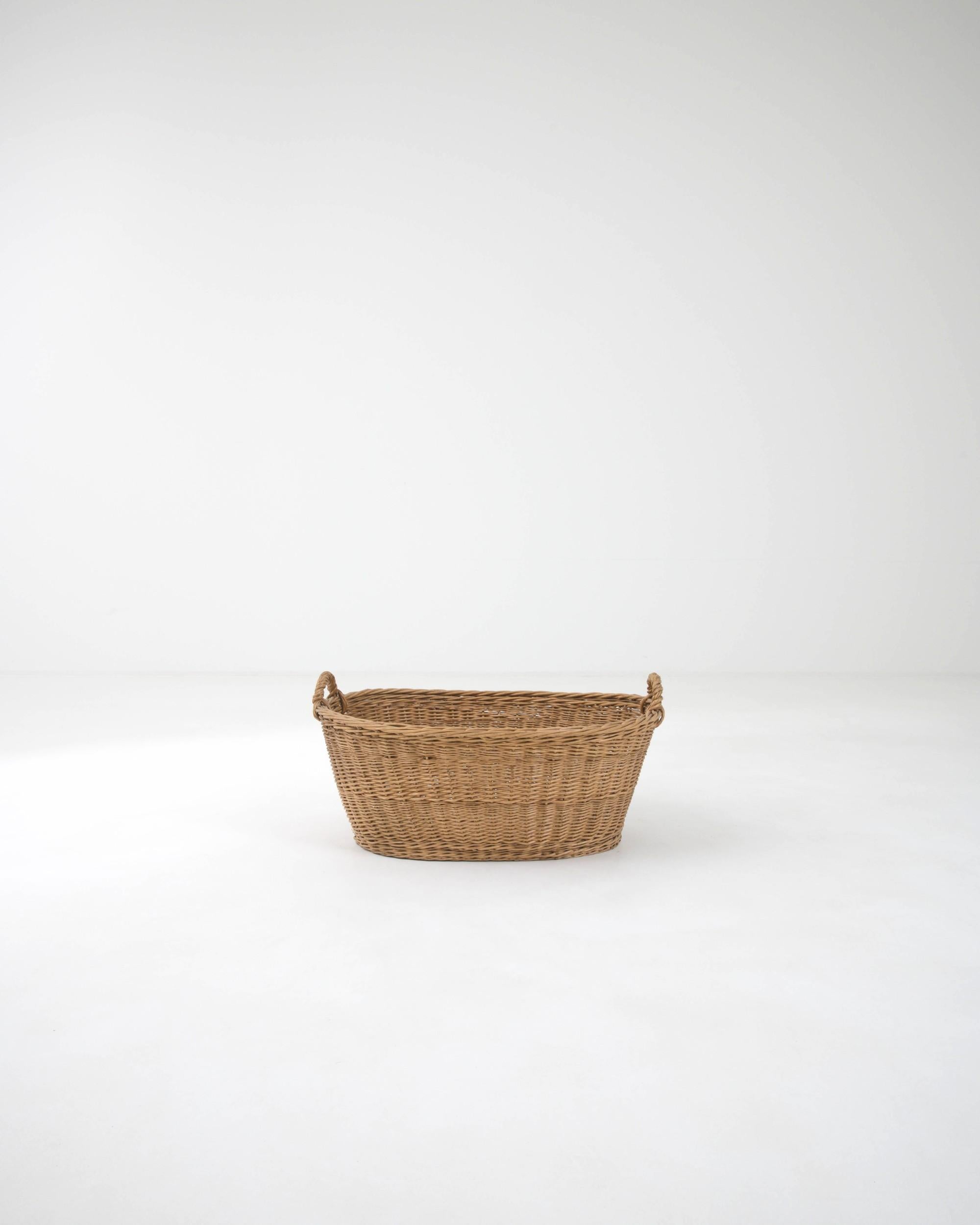 Hand-woven in France in the early 20th century, this wicker basket boasts a practical shape while the craftsmanship of the weaving technique imparts a sense of rustic coziness.Light and easily transportable, this classic wicker basket is ready to