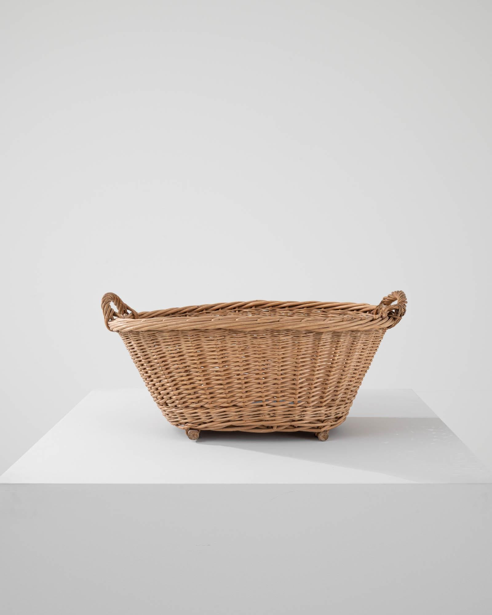 Hand-woven in France in the early 20th century, this wicker basket boasts a practical shape while the craftsmanship of the weaving technique imparts a sense of rustic coziness.Light and easily transportable, this classic wicker basket is ready to